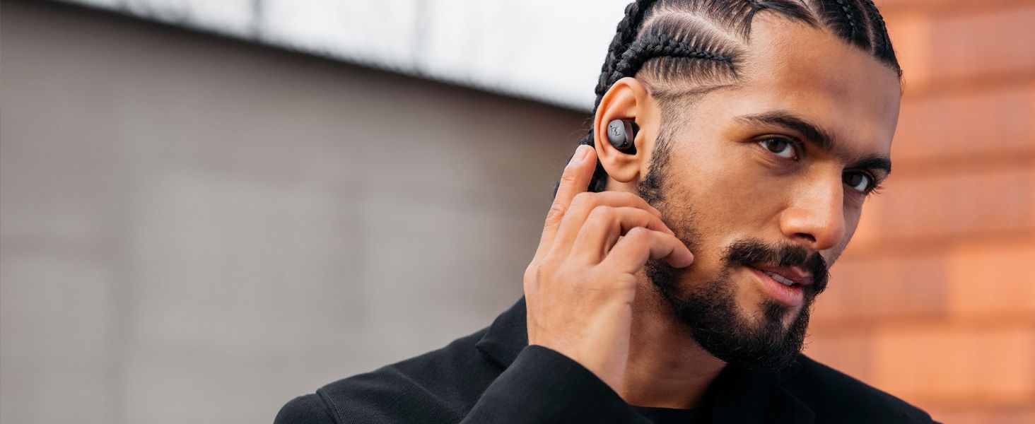 Shows a person wearing the earbud in a real-world setting so shoppers can picture using it day to day.
