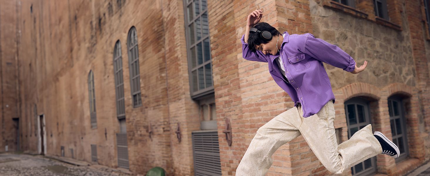 Shows the wireless headphones in an energetic city moment to help shoppers picture them in active daily life.