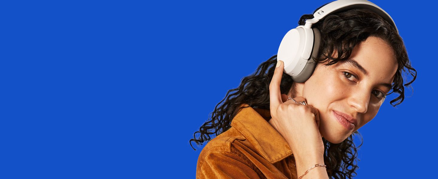 Shows a smiling listener wearing the headphones against a bold backdrop to help shoppers see the product worn in daily life.