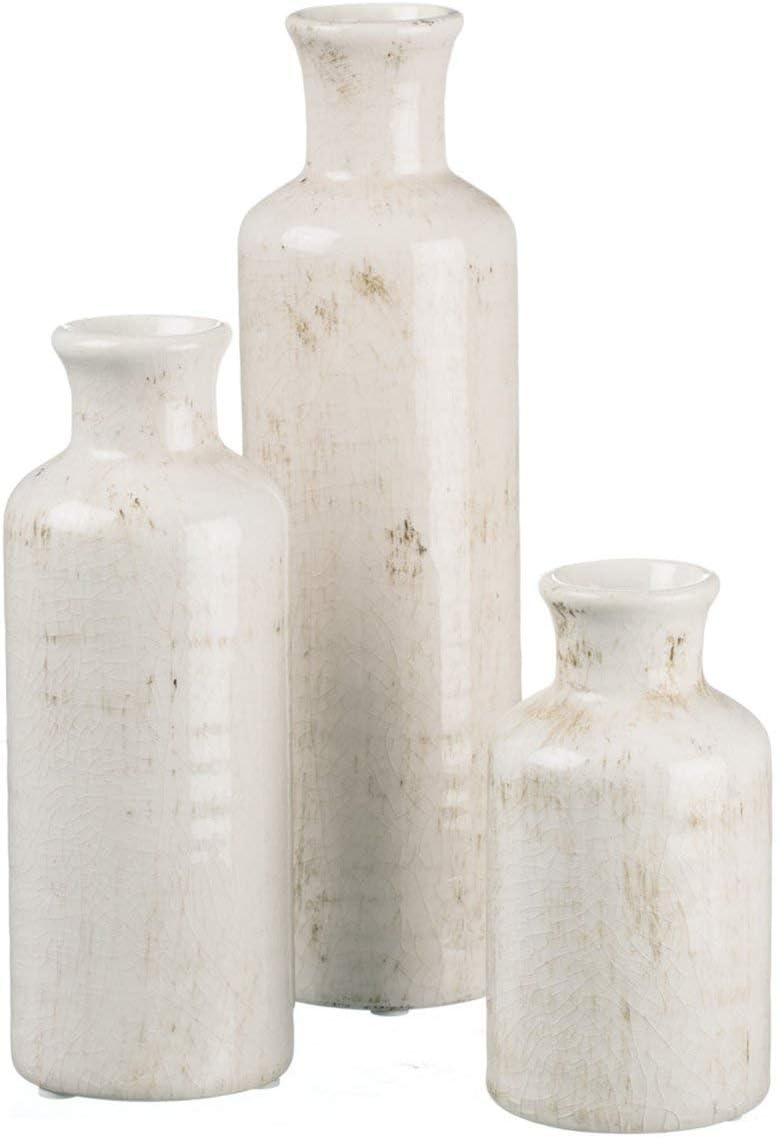 Showcases a set of three white ceramic vases with a distressed finish to highlight their rustic, vintage-inspired design.