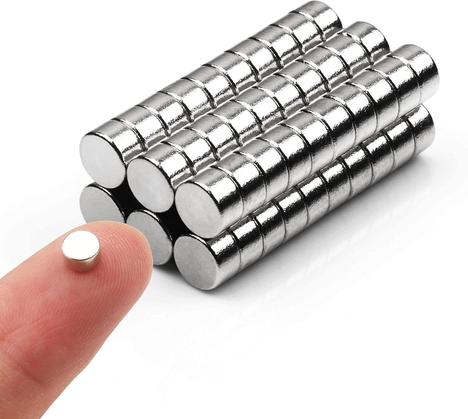Shows the core product clearly - a set of small cylindrical neodymium magnets arranged in rows, demonstrating the quantity included in the purchase. Uses a human finger holding one magnet to provide…