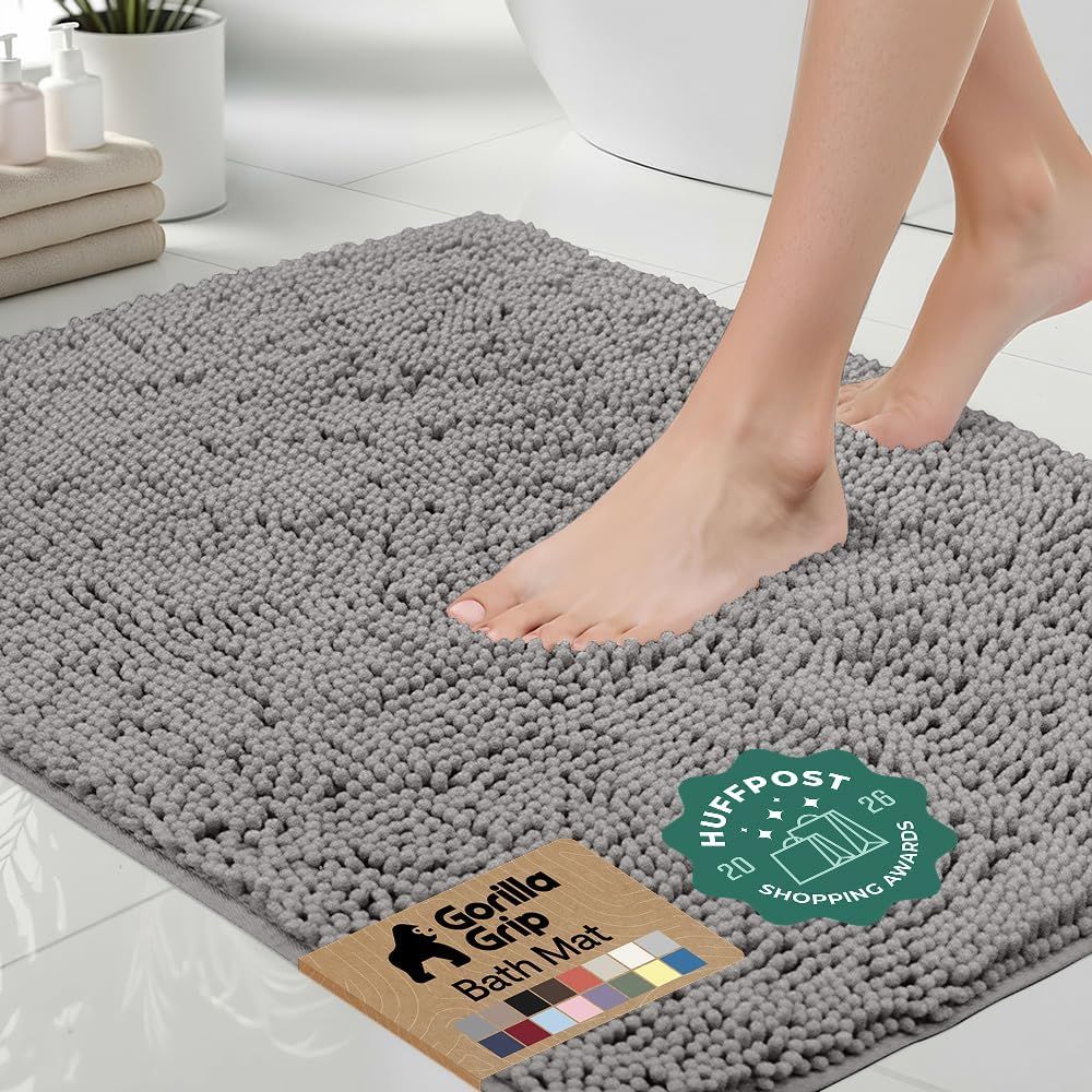 Shows a person standing on the bath mat to demonstrate its size, texture, and real-world use, helping shoppers visualize how it looks and feels underfoot. Displays the bath mat in a realistic…