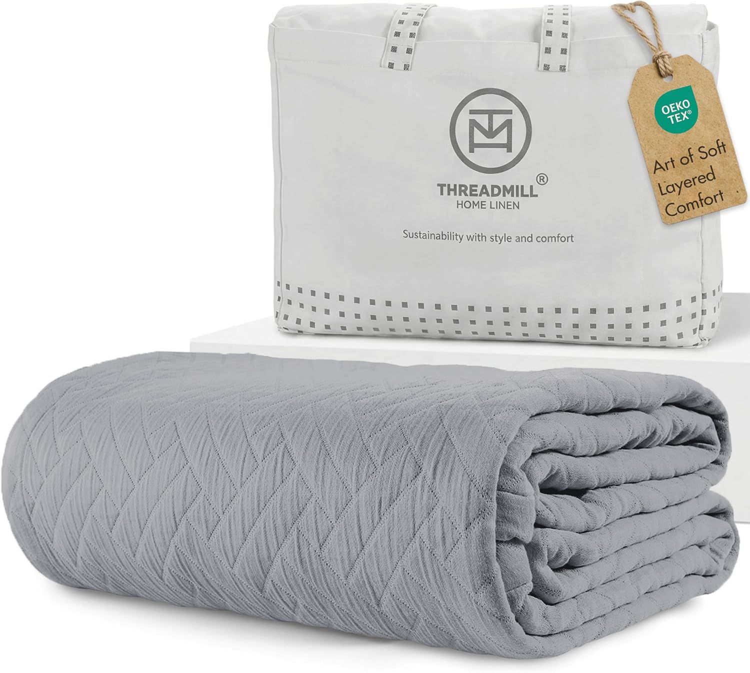 Displays the core product, a gray quilted blanket, clearly showing its texture and quality to help shoppers understand what they are purchasing. Shows the retail packaging and storage bag that comes…