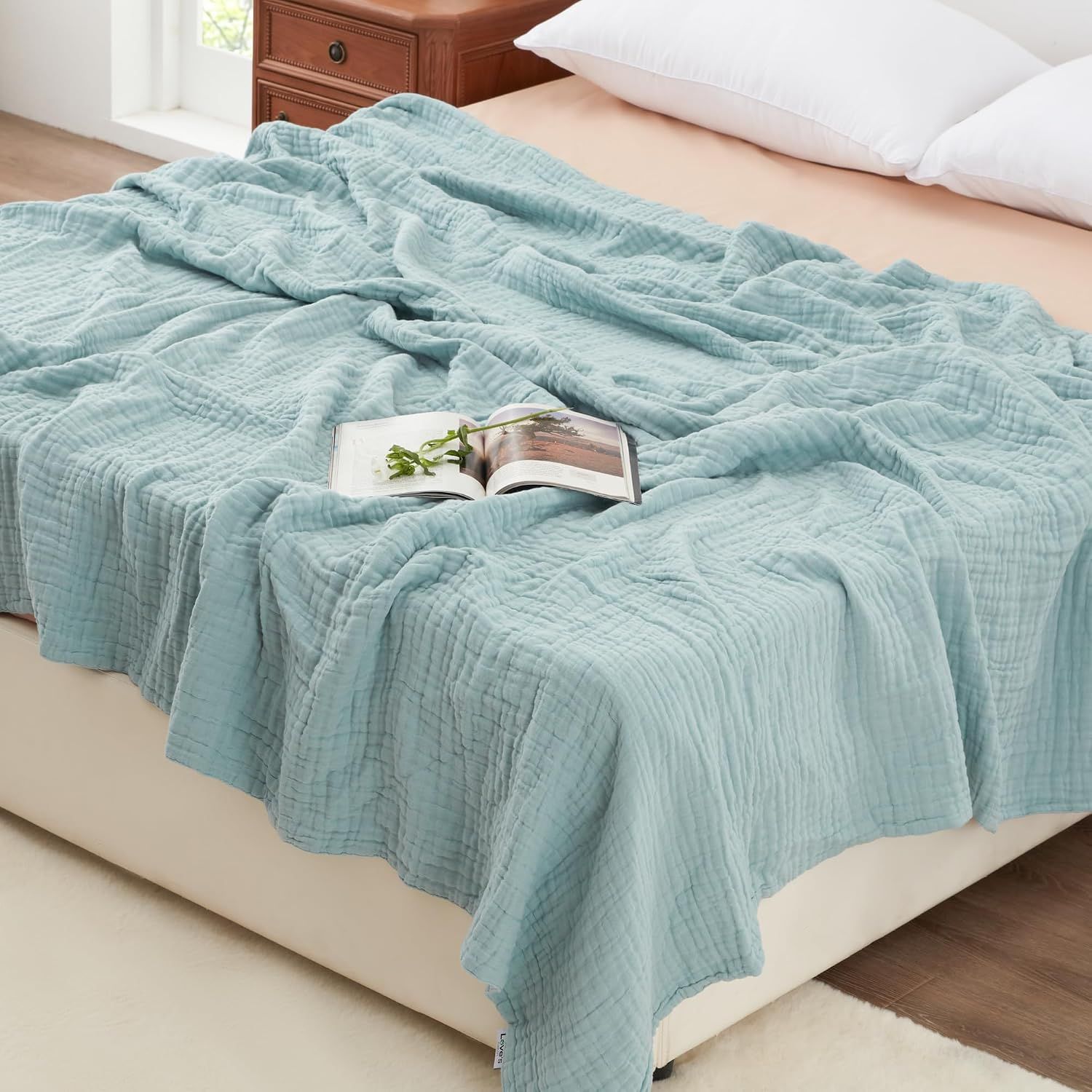 Displays the core product, a soft quilted blanket in a calming blue-green color, to show shoppers its texture, drape, and appearance on a bed. Shows the blanket styled in a realistic bedroom…