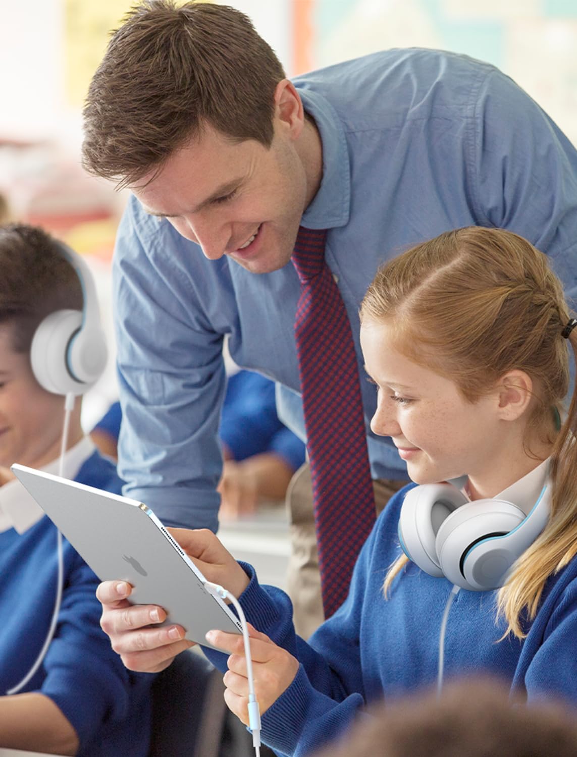 Depicts a realistic classroom environment with a teacher assisting students, conveying an authentic, relatable use case for the product.