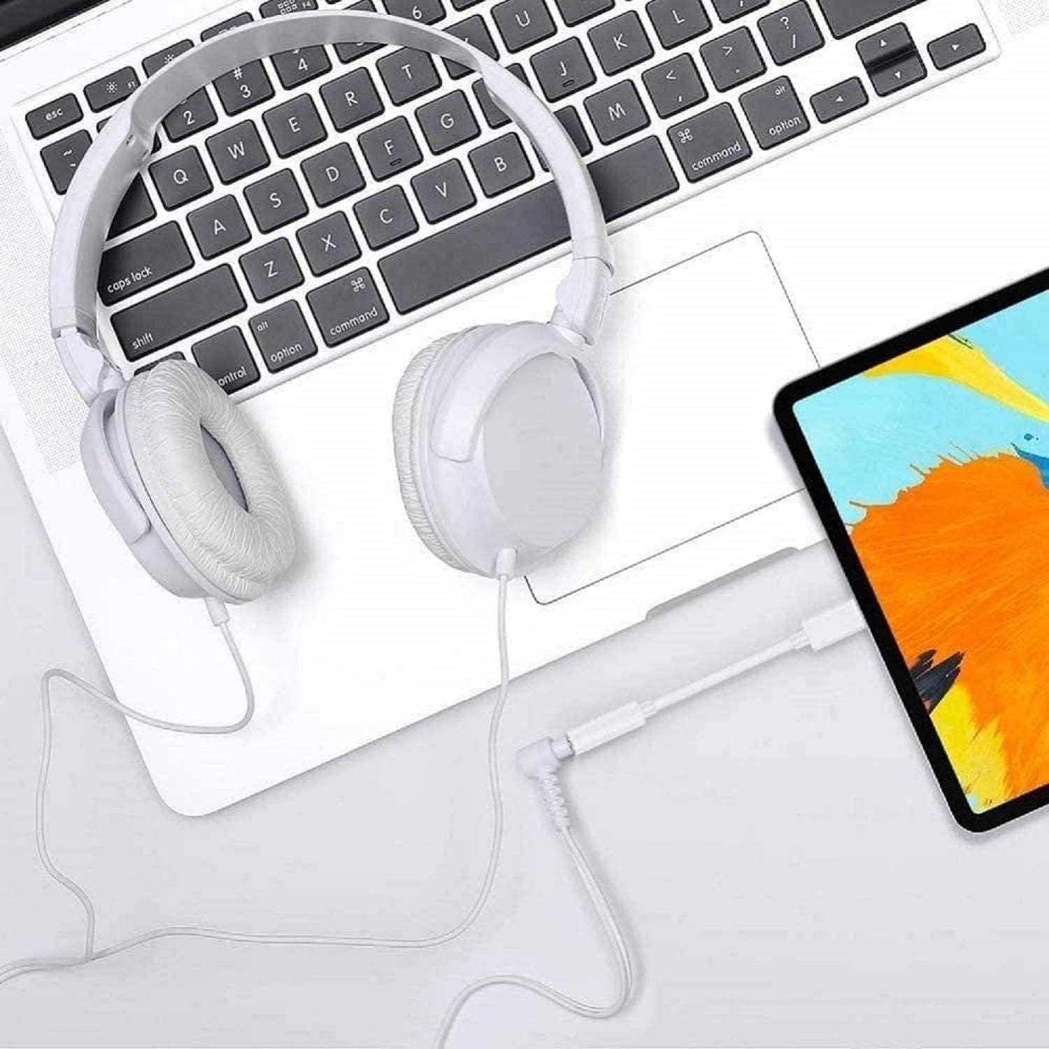 Shows the product (headphones) in a realistic usage context alongside a keyboard and tablet, demonstrating its compatibility and integration with other devices.