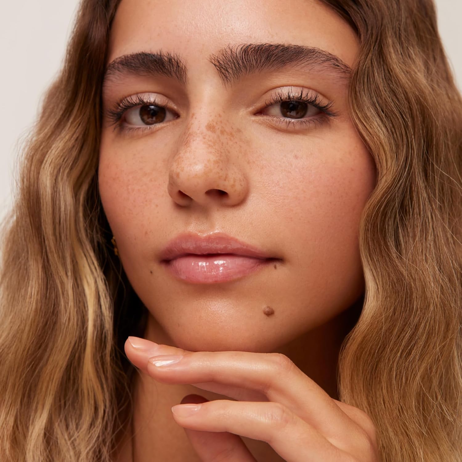 Showcases the product's ability to enhance natural beauty, emphasizing a fresh-faced, minimal makeup look with visible freckles and glowing skin.