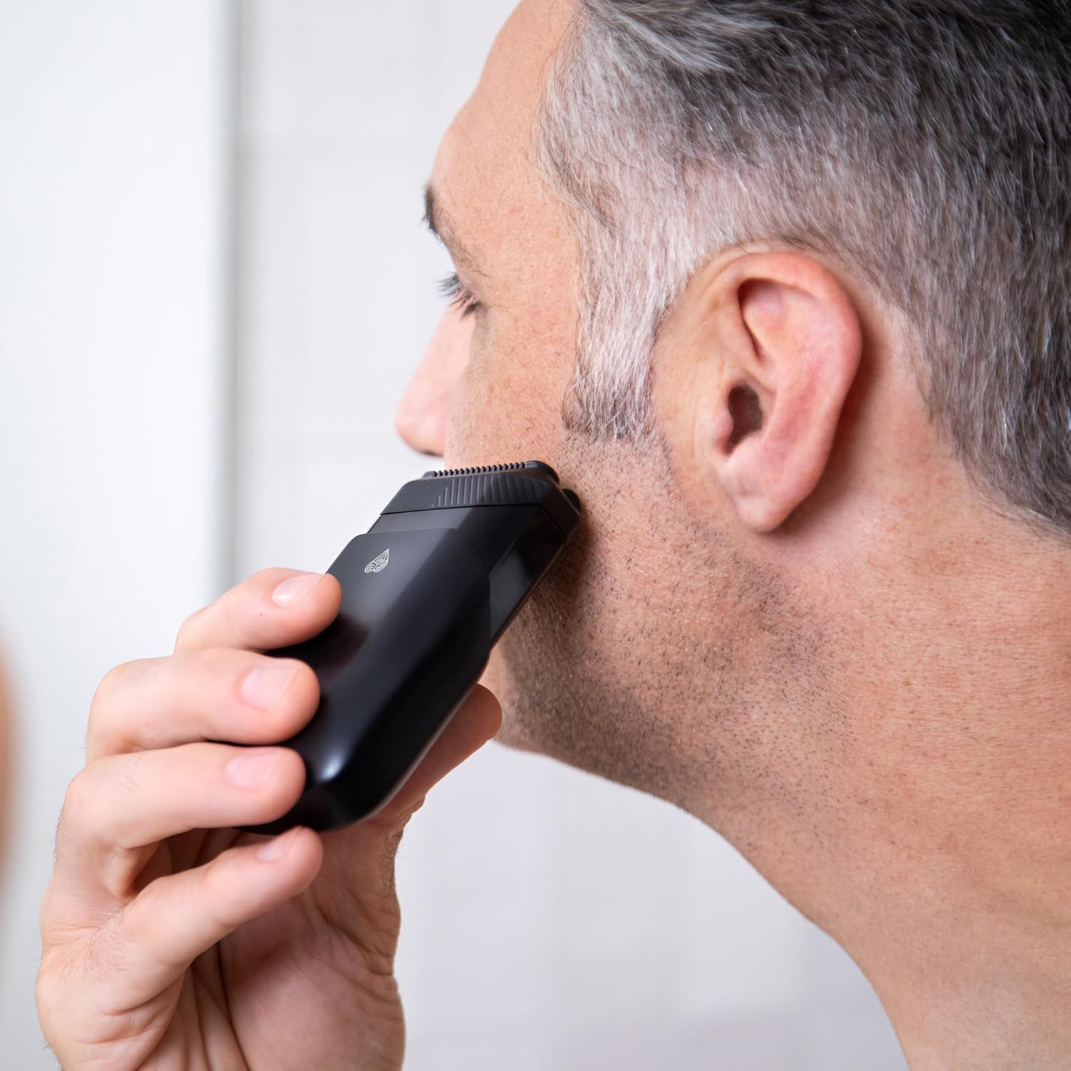 Shows the electric trimmer being used on facial hair, demonstrating its practical application and ease of use for personal grooming.