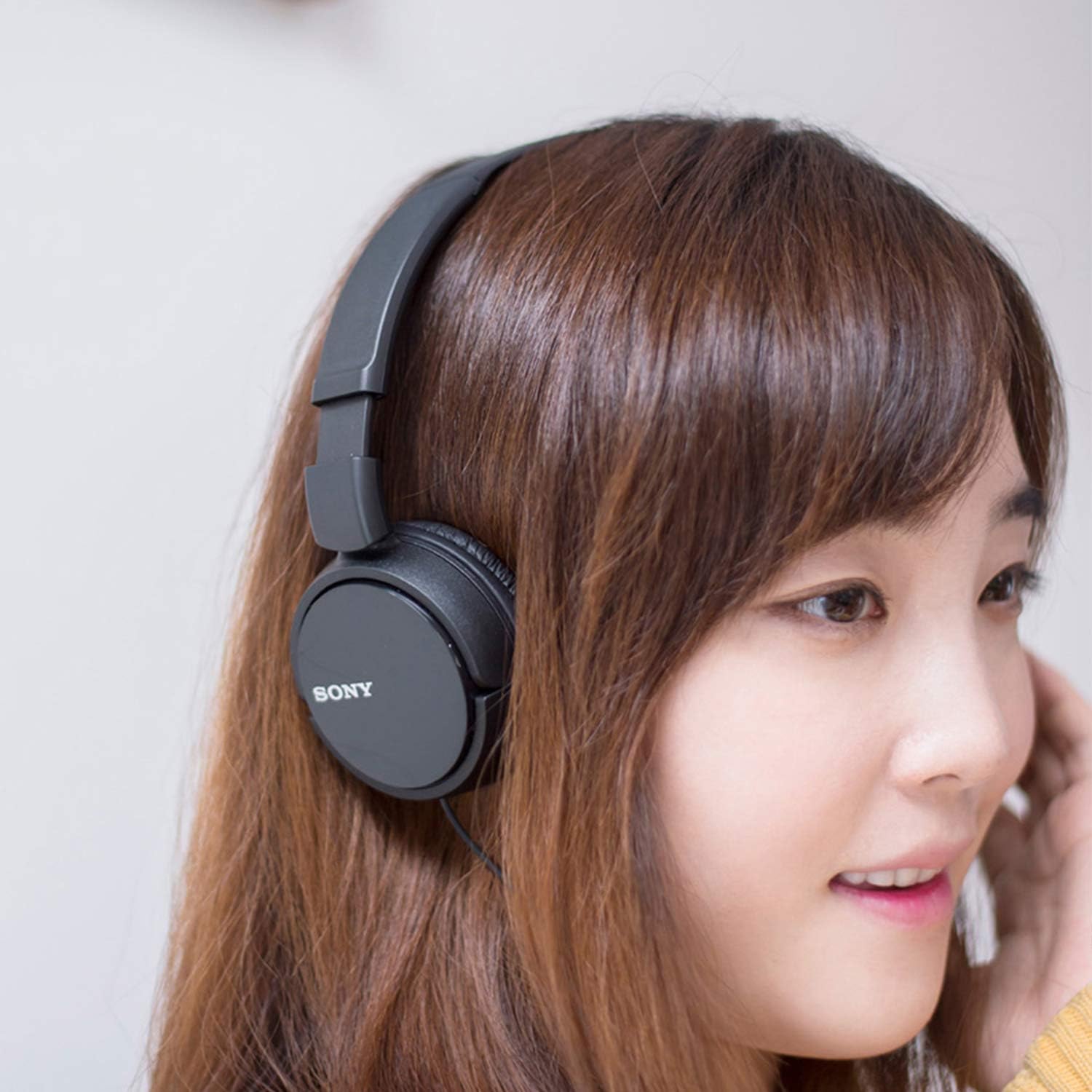 Shows a person wearing Sony headphones to demonstrate how they look when worn and their comfort.