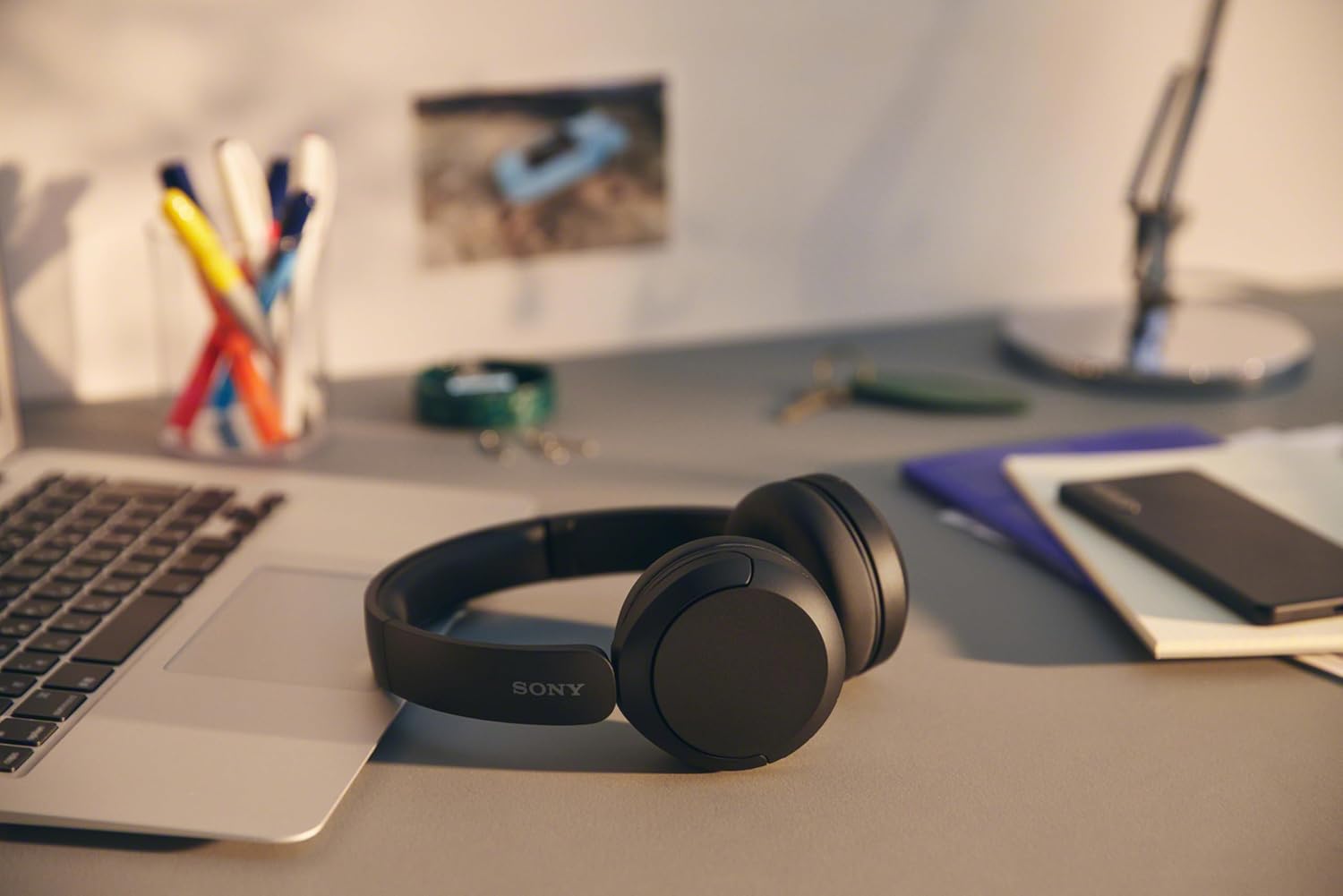 Shows the headphones in a realistic home office environment to demonstrate their suitability for remote work and productivity. Illustrates how the headphones fit into a typical work-from-home setup,…