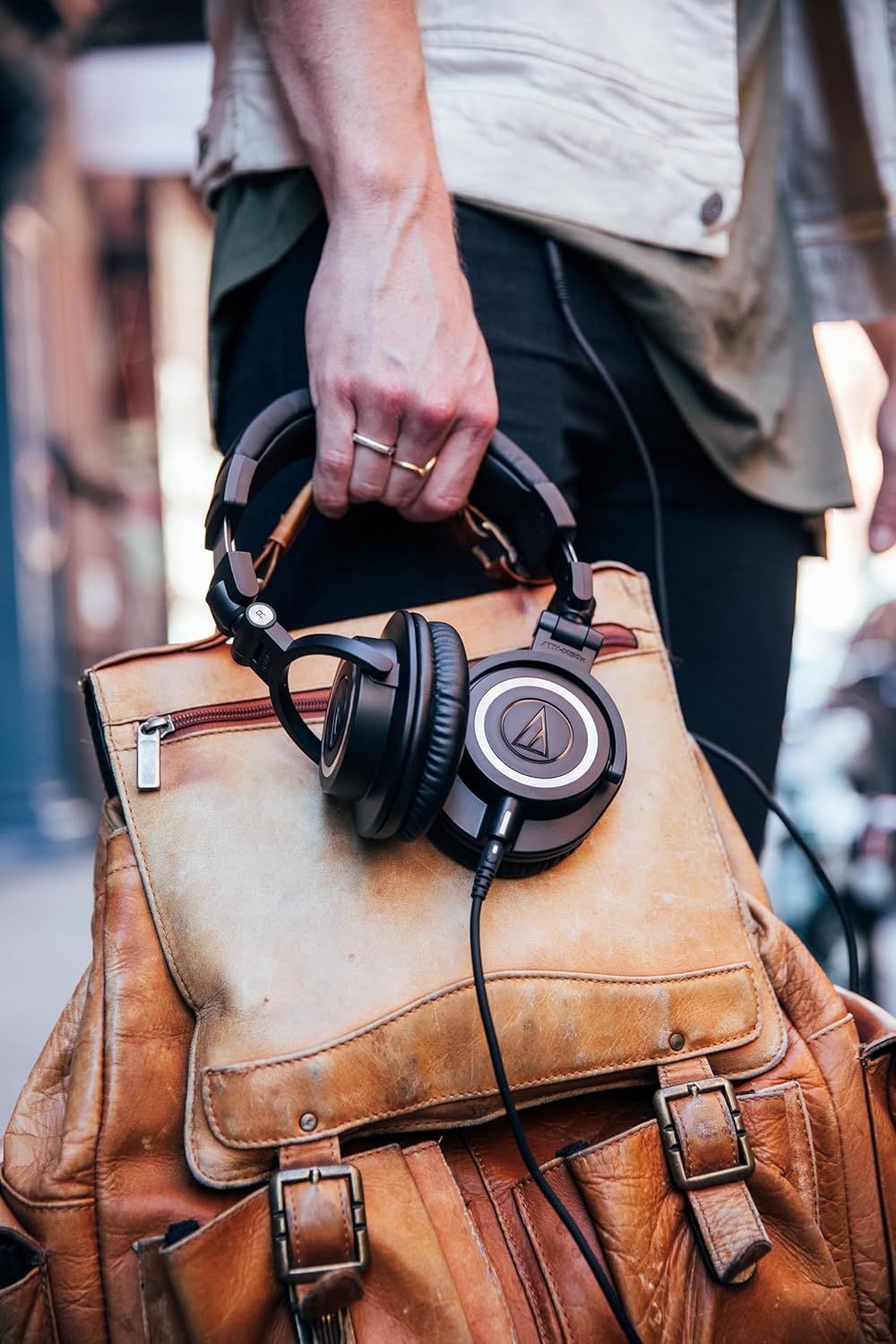 Shows the headphones in a real-world travel context to help shoppers visualize how the product fits into their daily lifestyle and portability needs.