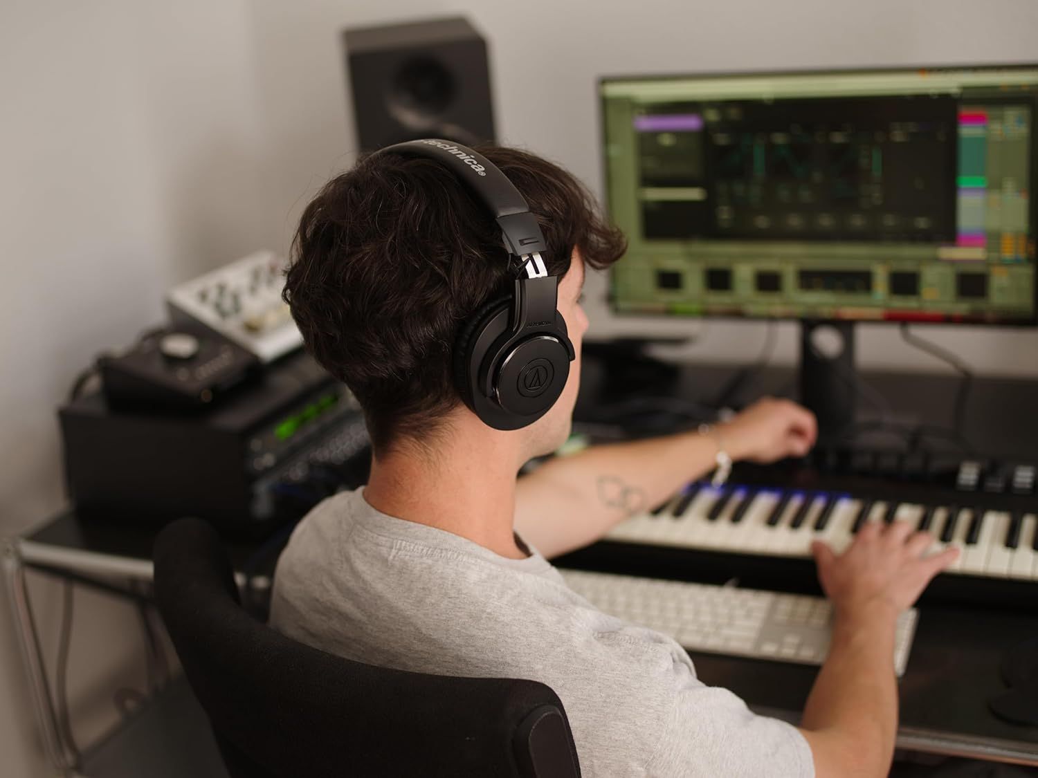 Shows the headphones being used in a real-world music production setting to help shoppers visualize the product in their own creative workspace.