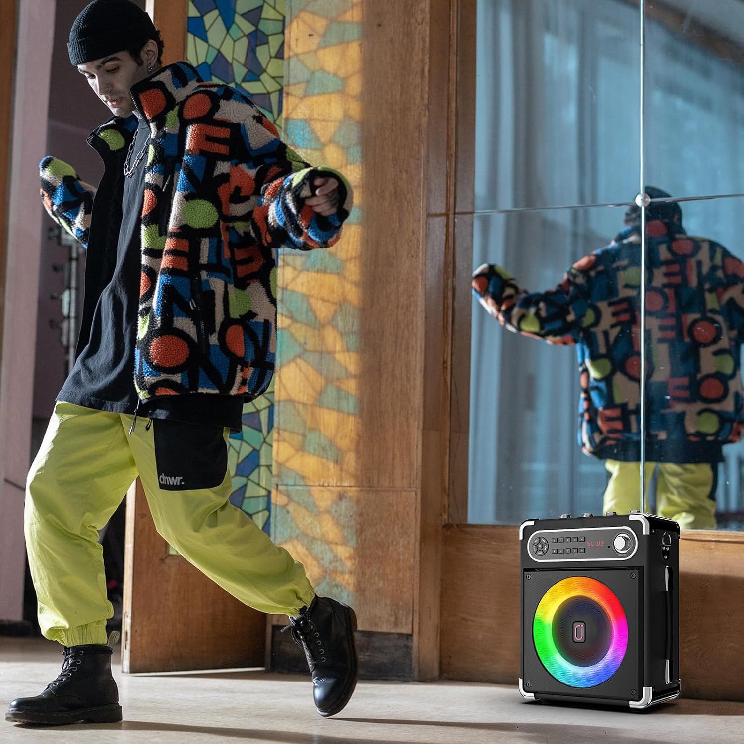 Shows the product being used in a real-world indoor setting with a young person, demonstrating its portability and appeal for casual listening and social environments.