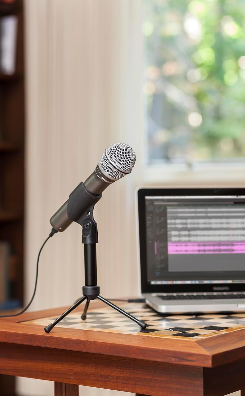 Shows the microphone in a realistic home or office setting with a laptop to help shoppers visualize how the product fits into their workspace for recording, podcasting, or video calls.