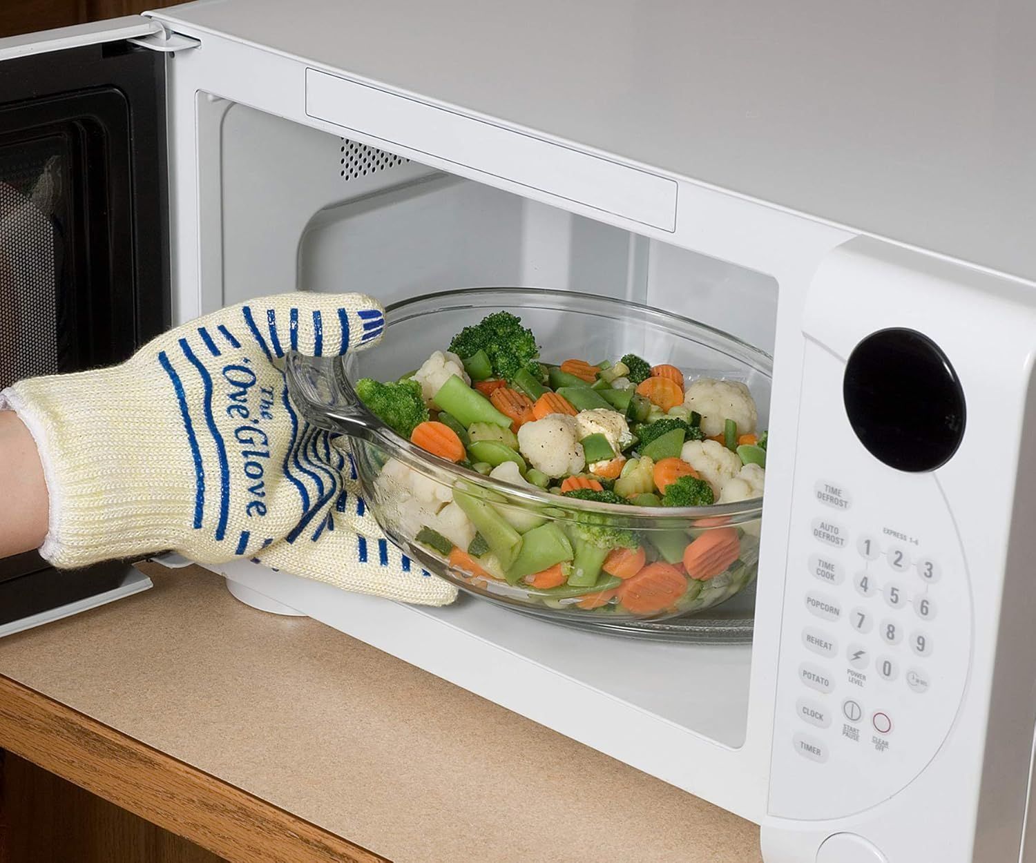 Demonstrates that the oven glove is safe and effective for handling hot dishes from the microwave, reassuring shoppers of its heat protection capability.