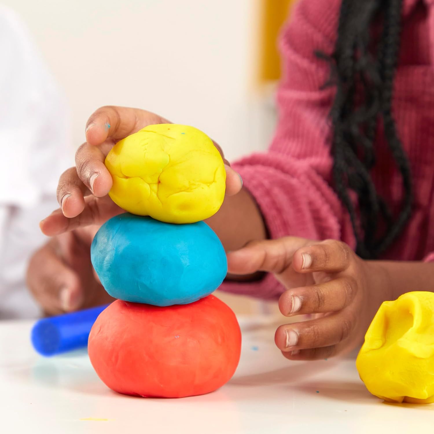 Shows the product in a real-world play context with a child actively using colorful play dough, helping shoppers visualize the product in use and its appeal…