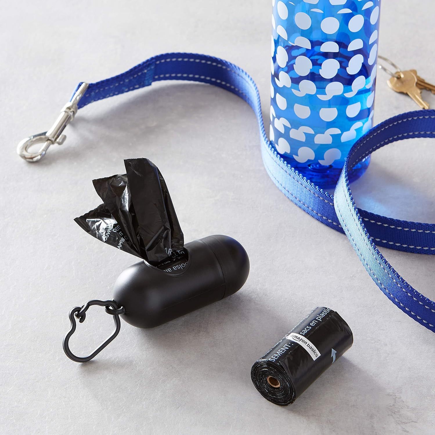 Shows all the items included in the dog walking kit to help shoppers understand the complete package they will receive, including the dispenser, bags, leash attachment, and water bottle holder.