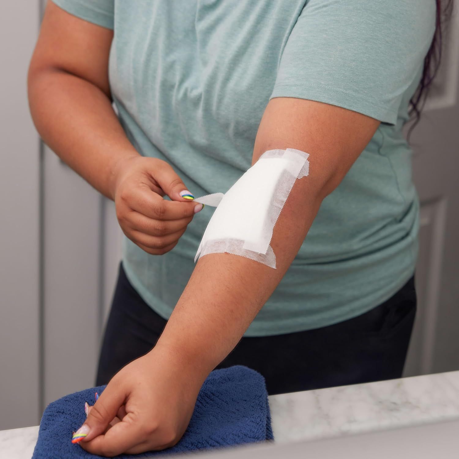 Demonstrates how to properly apply the bandage or patch to the arm, reassuring shoppers that the product is easy to use.