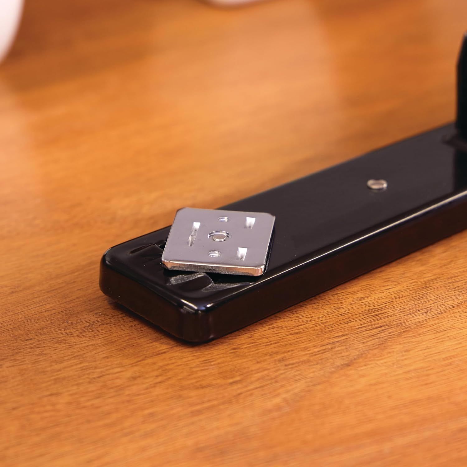 Demonstrates the physical mounting component and attachment mechanism of the product, showing how the metal plate integrates with the black base to provide secure installation or connection.