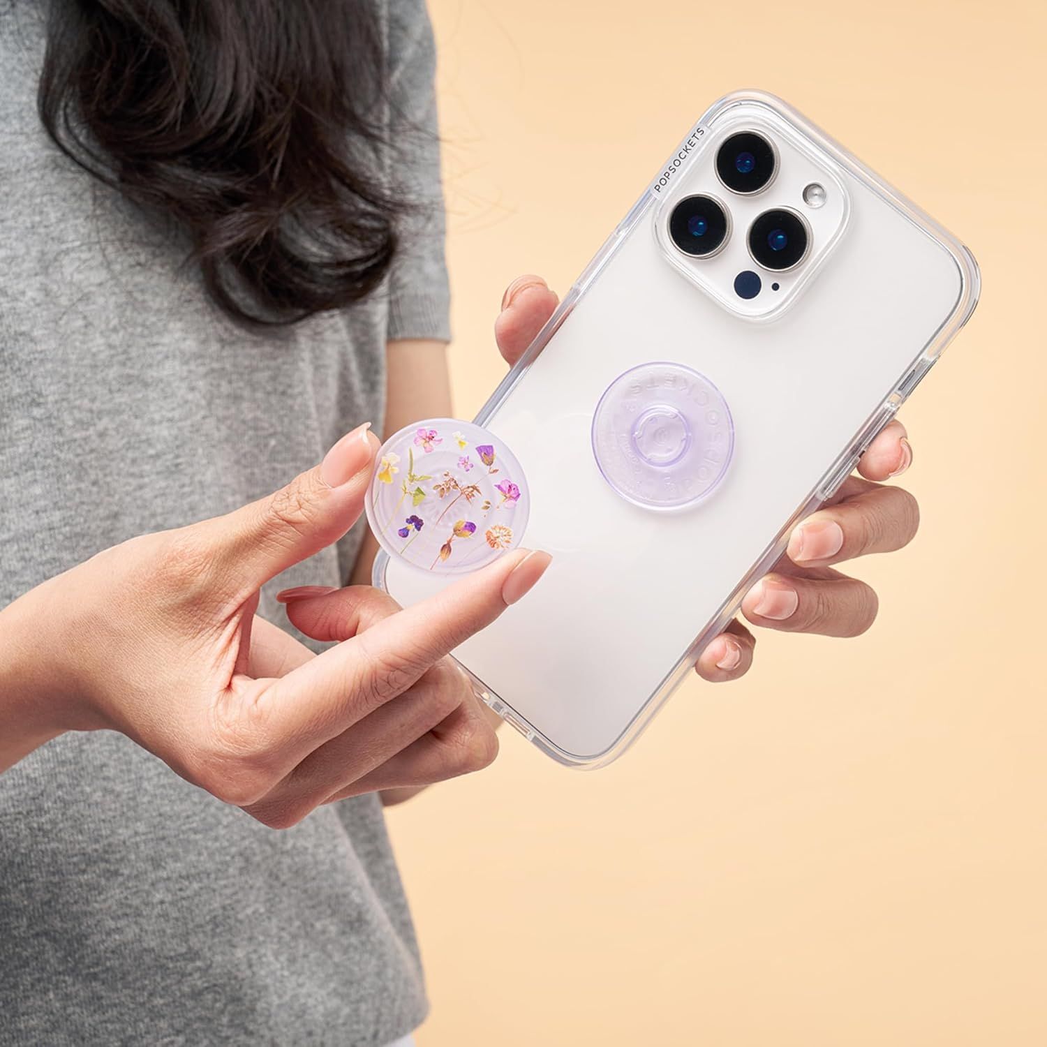 Demonstrates the product's swappable PopSocket feature, showing how users can easily customize their phone case with different decorative designs.