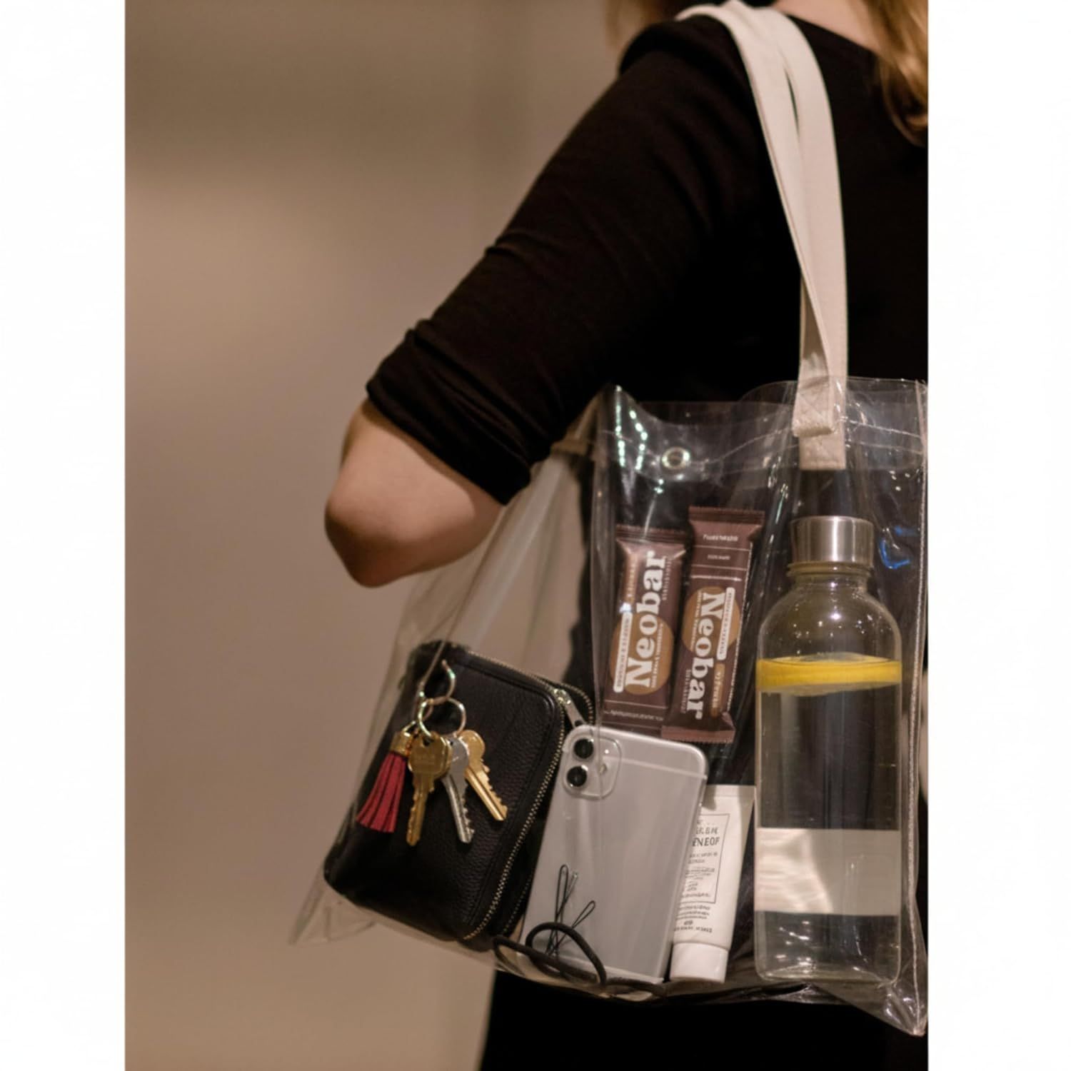 Demonstrates the product being used in a real-world context, showing how the transparent tote bag can carry everyday items like a wallet, phone, water bottle, and personal care products.