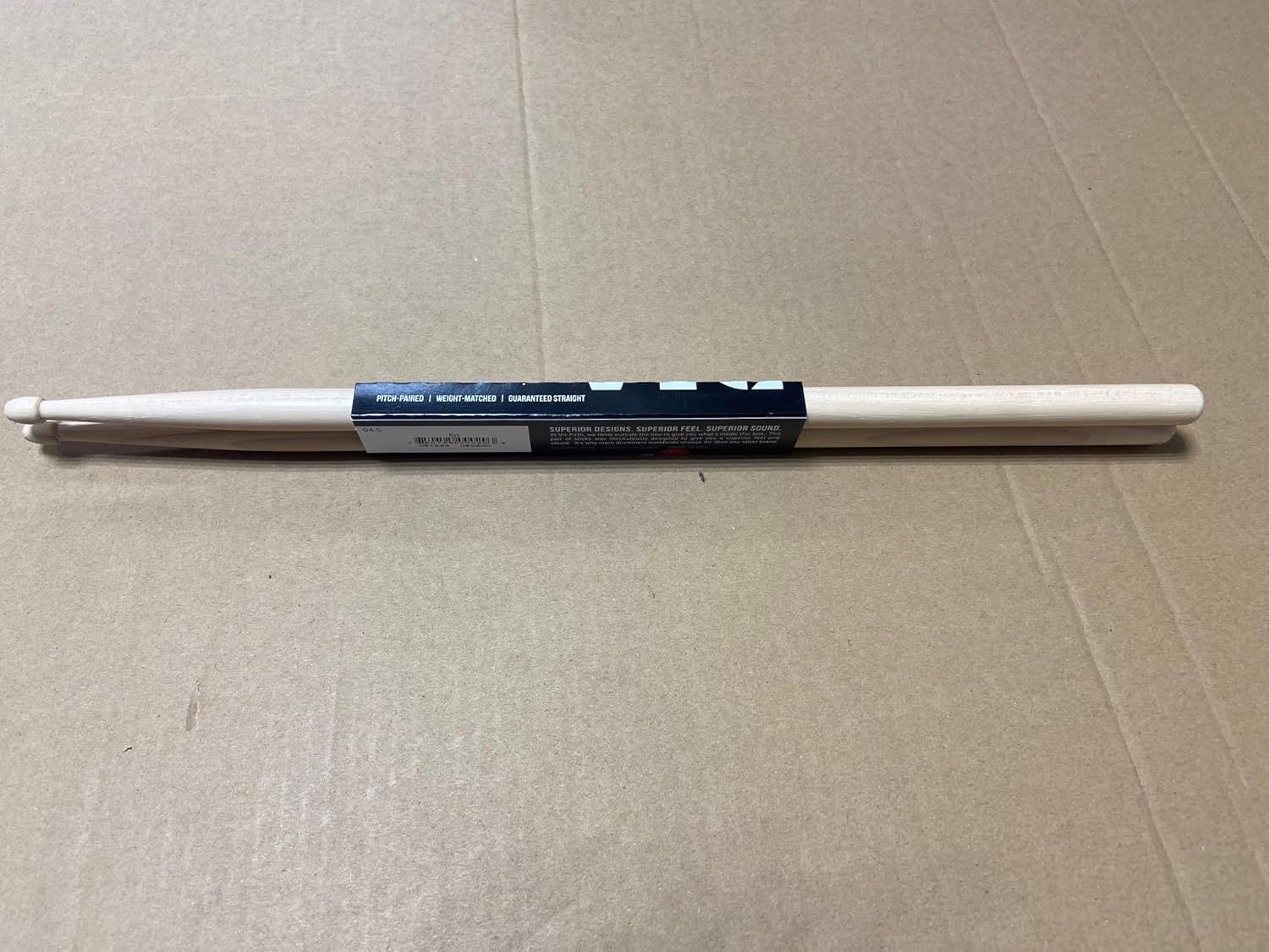 Shows the drumsticks alongside their packaging to demonstrate what the customer receives and highlight key product features like pitch-paired, weight-matched, and guaranteed straight.