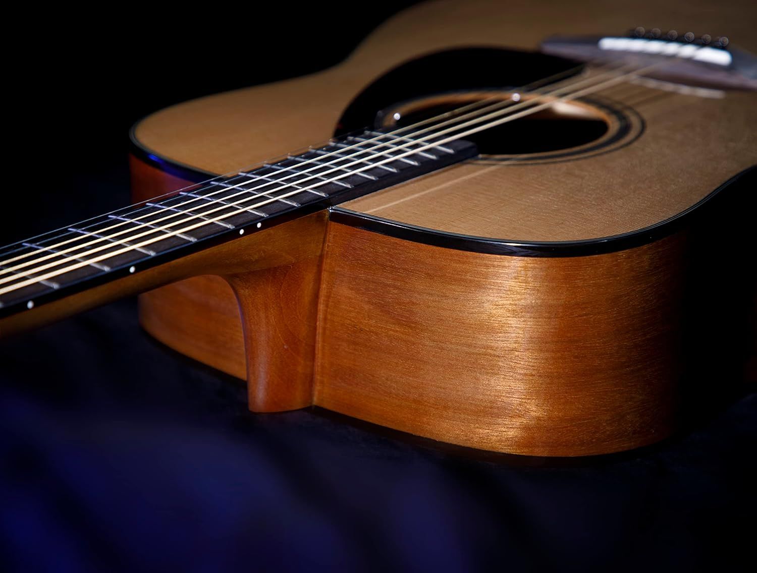 Showcases the acoustic guitar in an artistic, professional setting to emphasize its craftsmanship, premium wood finish, and aesthetic appeal to potential buyers.