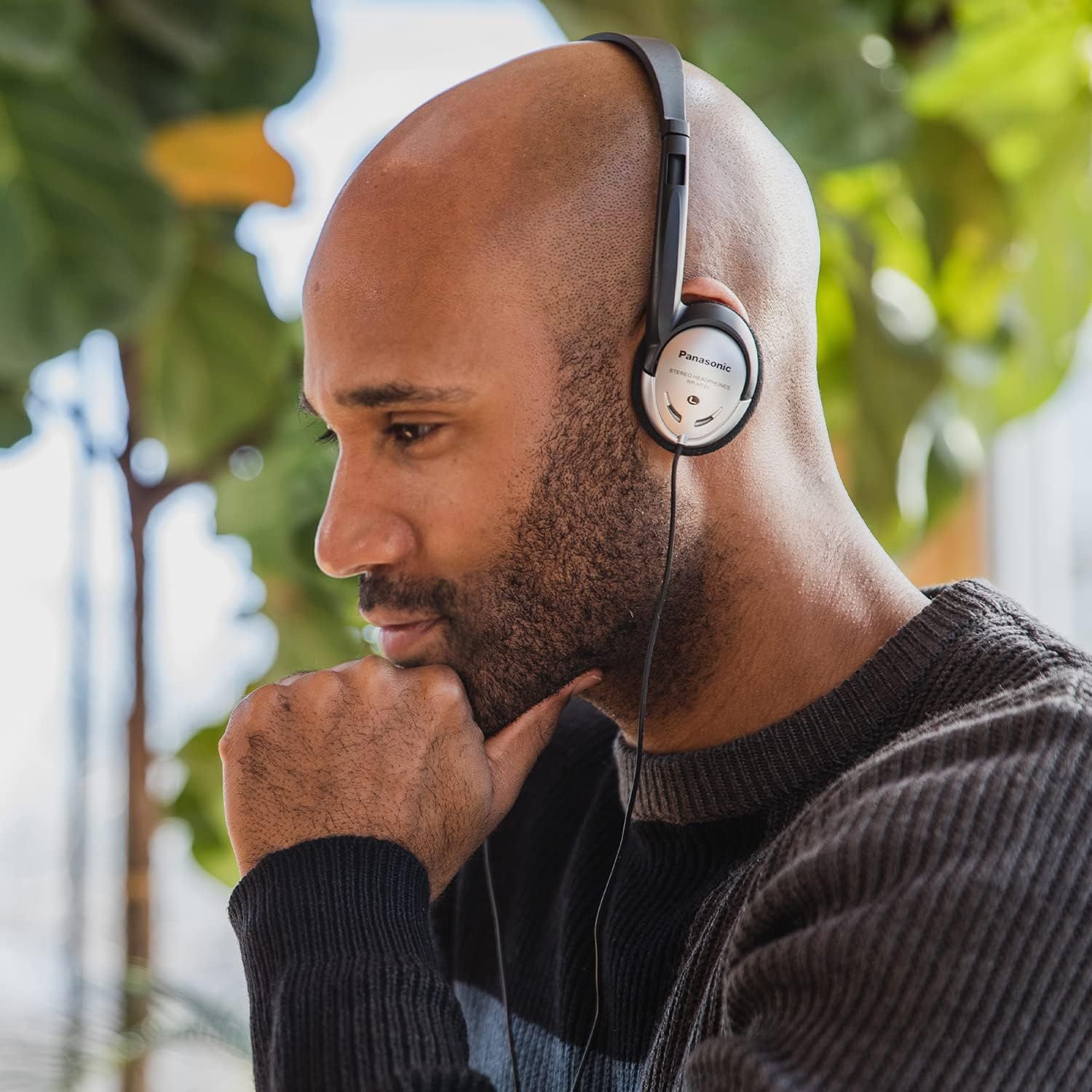 Shows the product being used in a natural outdoor setting to help shoppers visualize themselves using the headphones in everyday life.