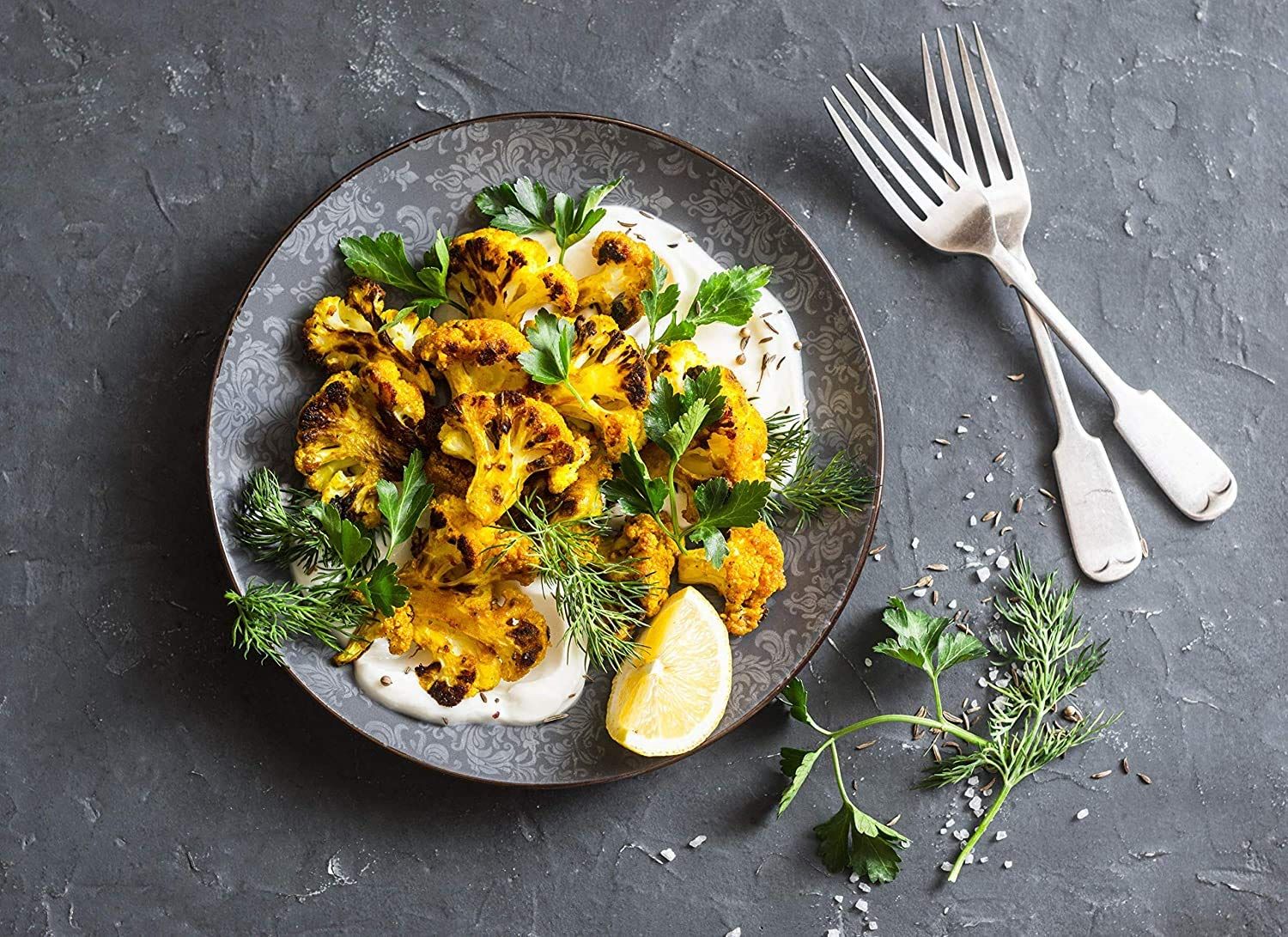 Showcases the product (likely roasted cauliflower or similar food item) in an appetizing, real-world dining context to help shoppers visualize the final…