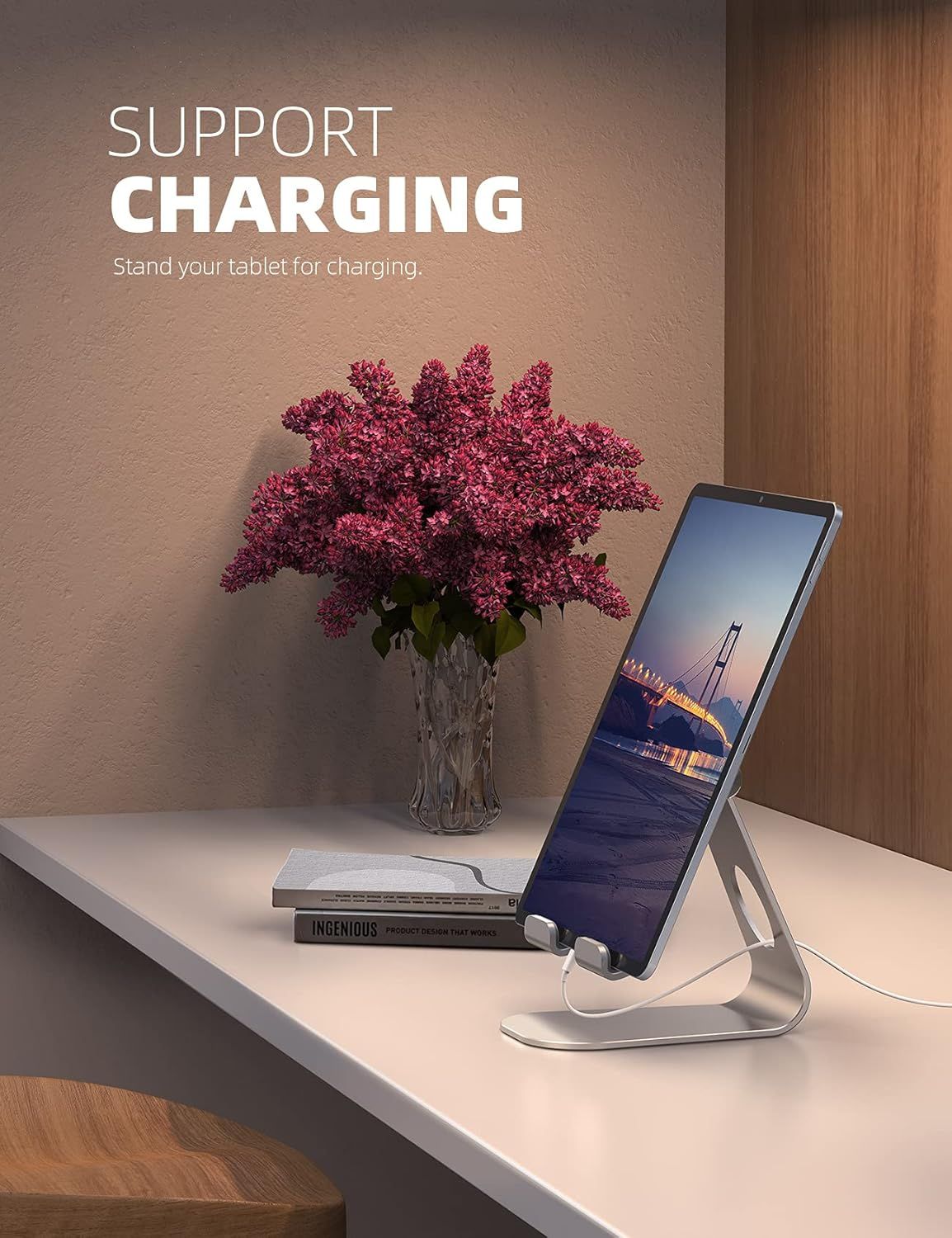Demonstrates that the tablet stand can hold and support a tablet while charging, showing a practical use case in a home or office environment. Shows the product in a real-world lifestyle context on…
