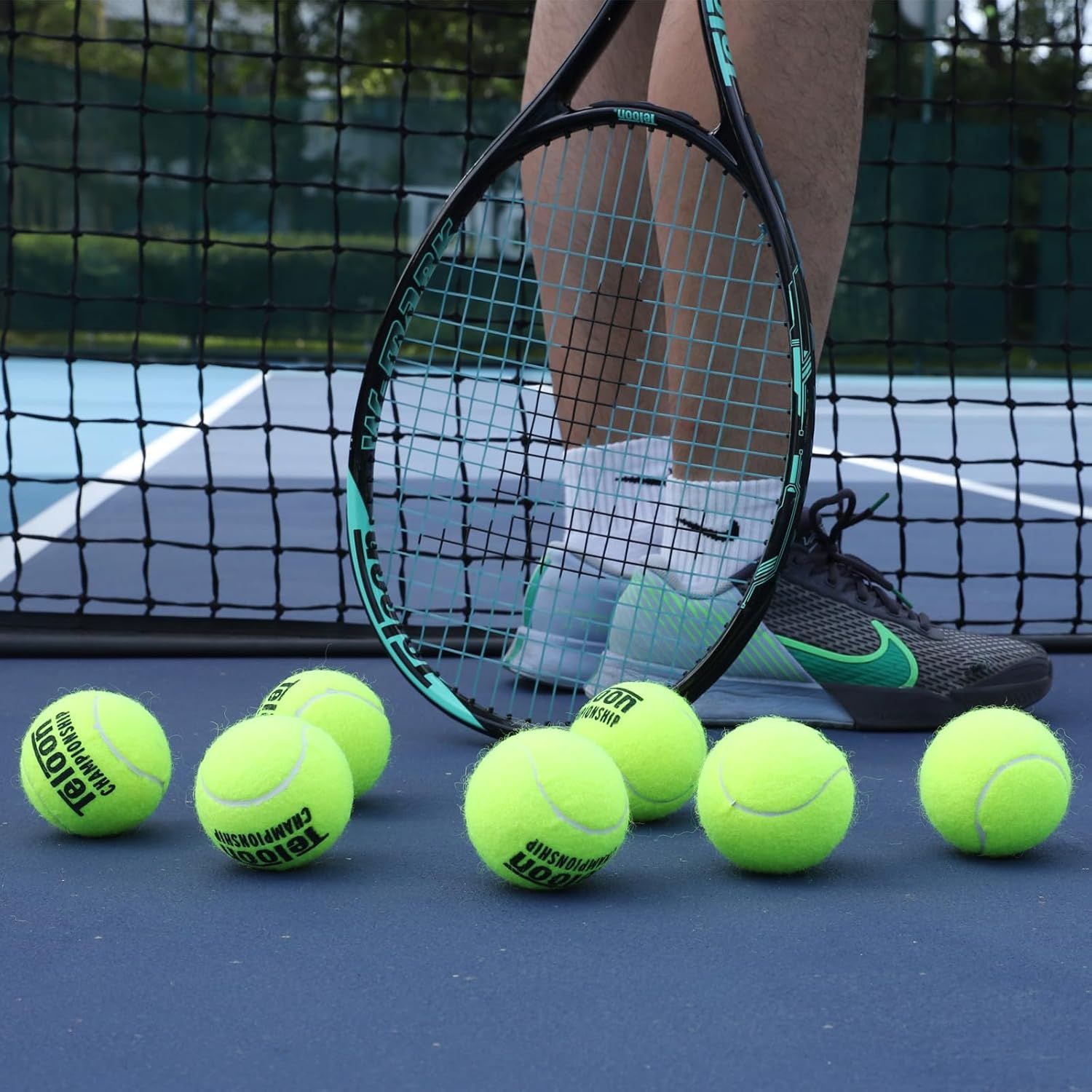 Shows the tennis racket and balls in an authentic on-court environment to help shoppers visualize the product in real-world use and create an aspirational connection with the sport.