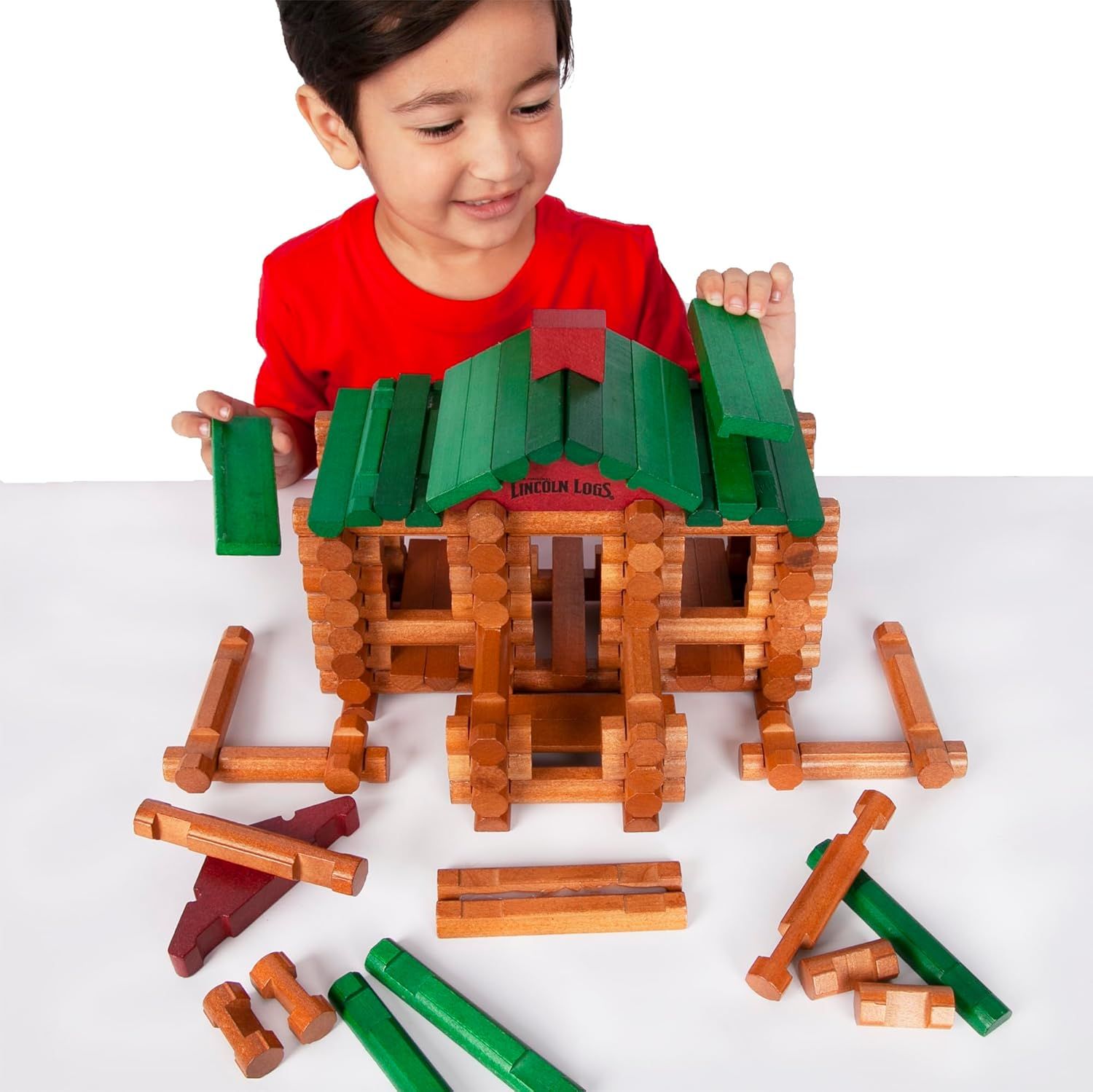 Shows the product in use by a child in a real-world context to help shoppers visualize how their child might engage with and enjoy the Lincoln Logs building…