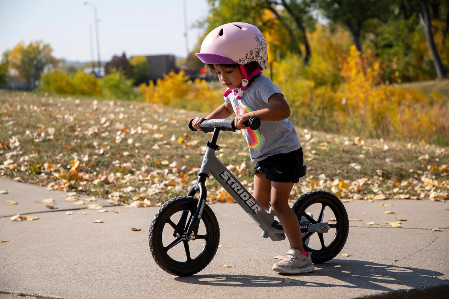 Shows the product in a natural, real-world setting to help shoppers visualize a child using the balance bike outdoors, building emotional connection and demonstrating practical use.