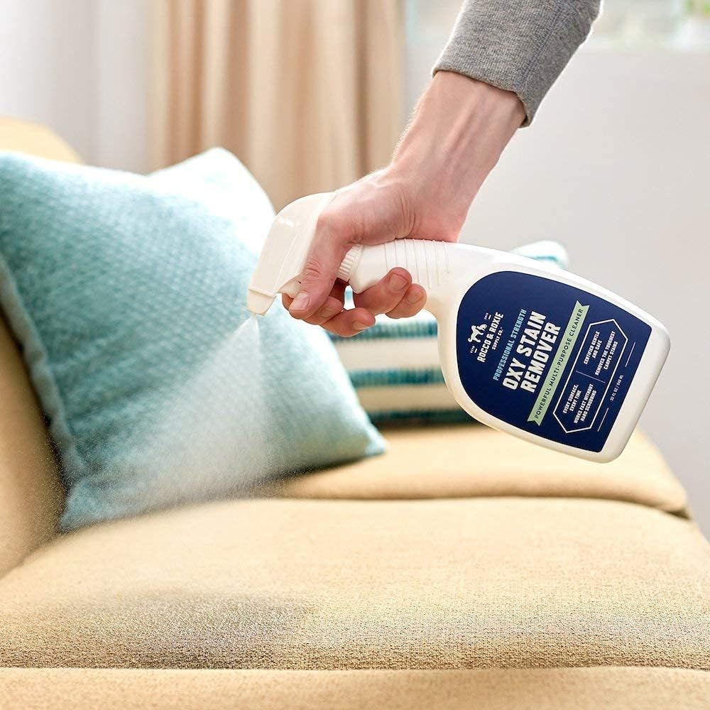 Shows the product being used in a real-world home setting on furniture, helping shoppers visualize how the dry stain remover works in their own living space.