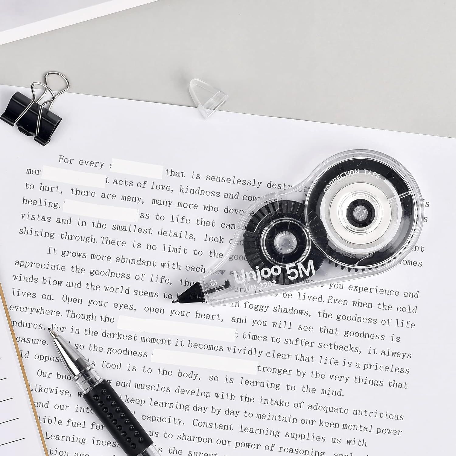 Displays the correction tape product alongside office accessories in a clean, catalog-style presentation to show the product clearly without distractions.