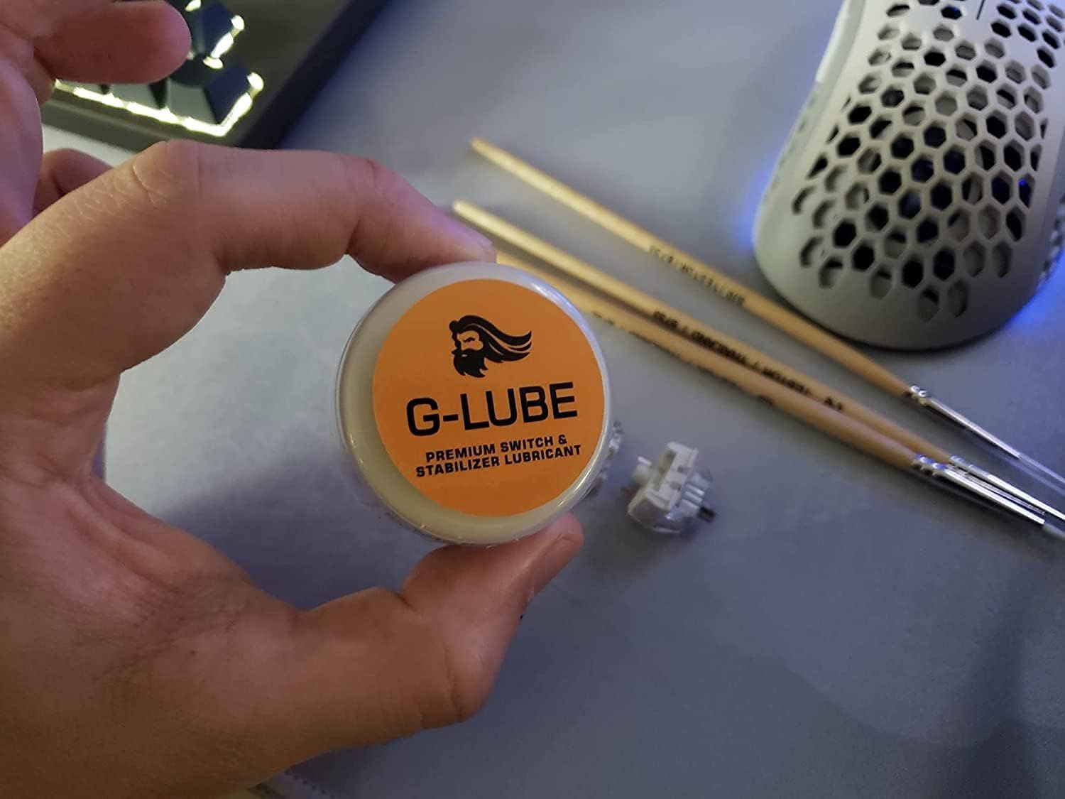 Shows the customer what items are included with the purchase: the G-LUBE lubricant container and two drumsticks, demonstrating this is a complete kit for drummers.