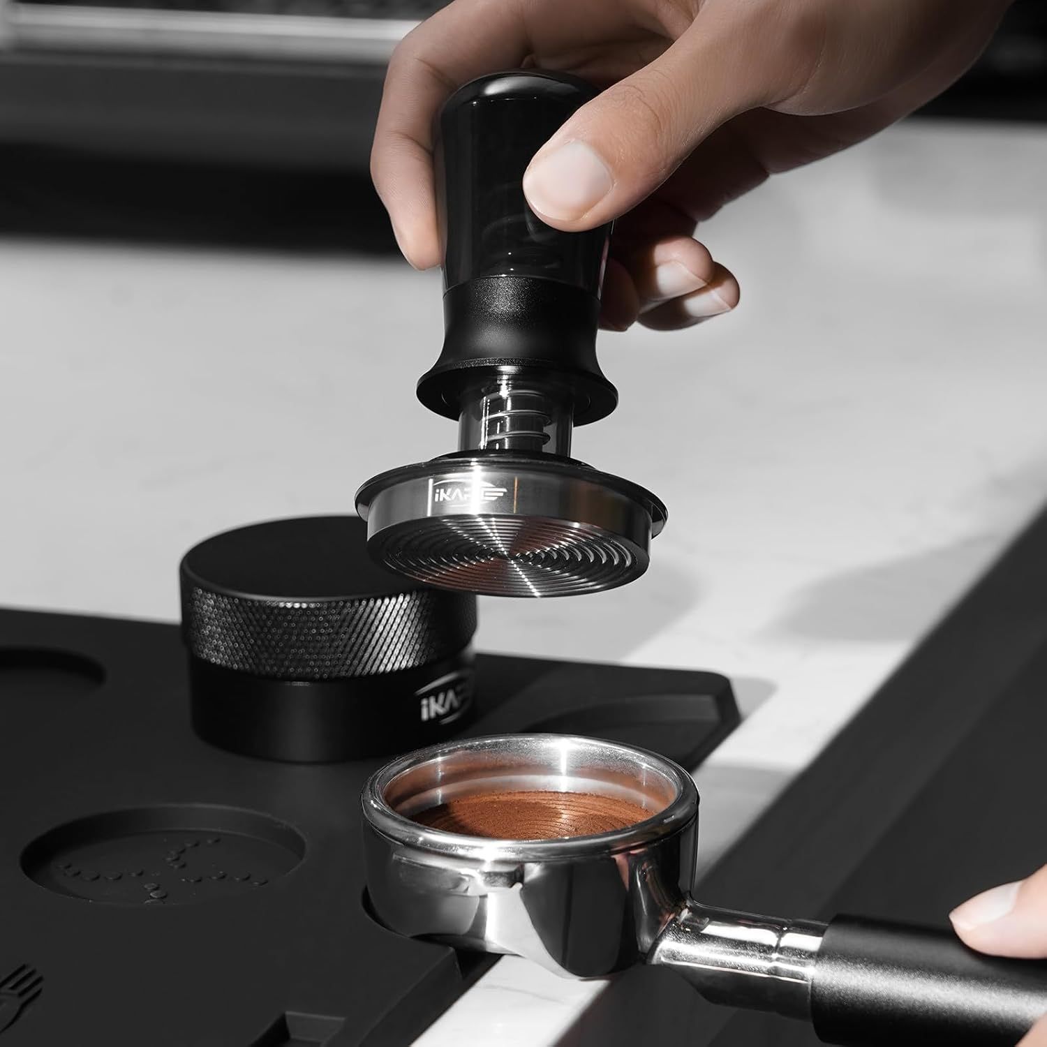 Demonstrates how to use the tamper with the portafilter, showing the ease of use and proper application technique.