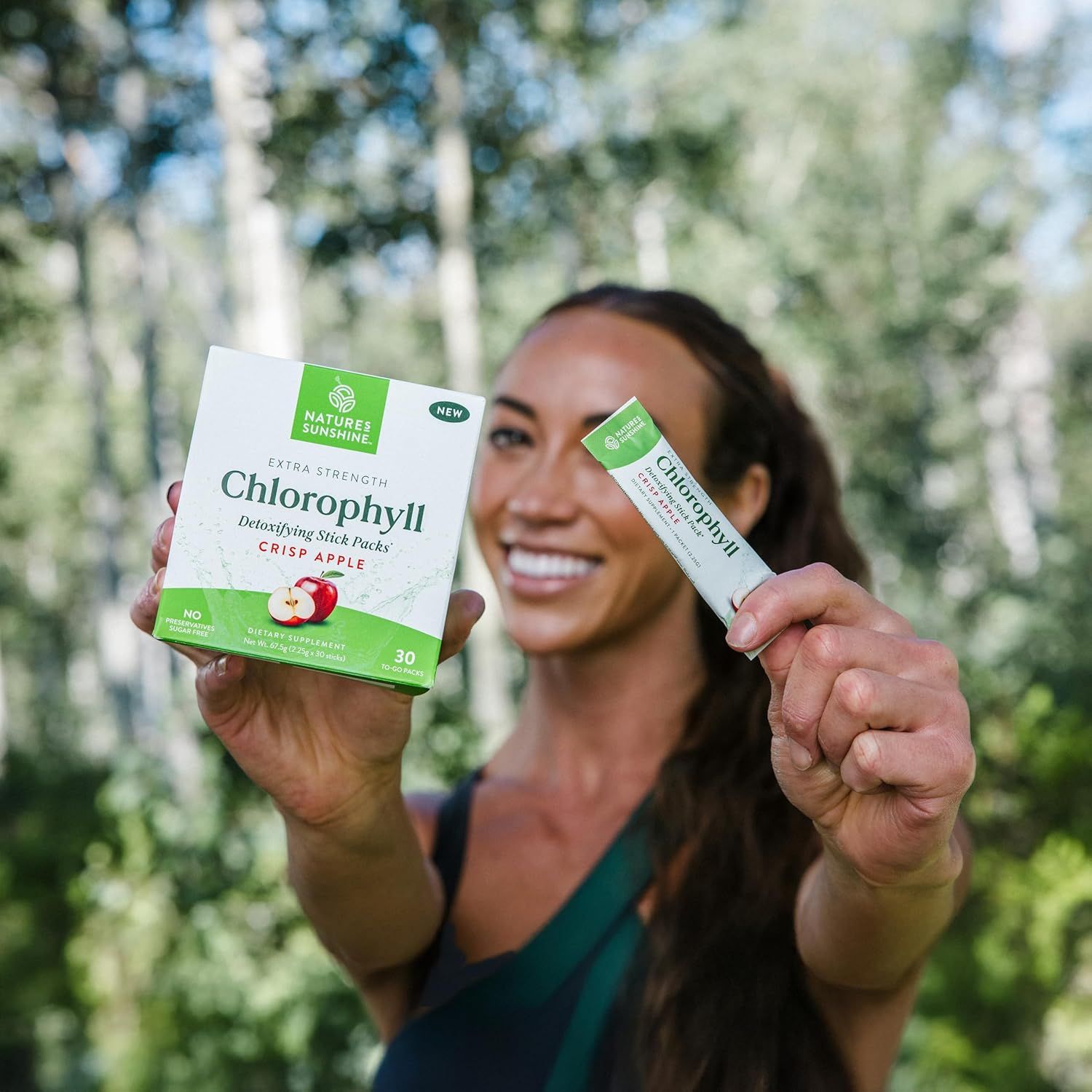 Shows a customer holding both the box and individual stick pack in an outdoor lifestyle setting to demonstrate the product format and create relatability.