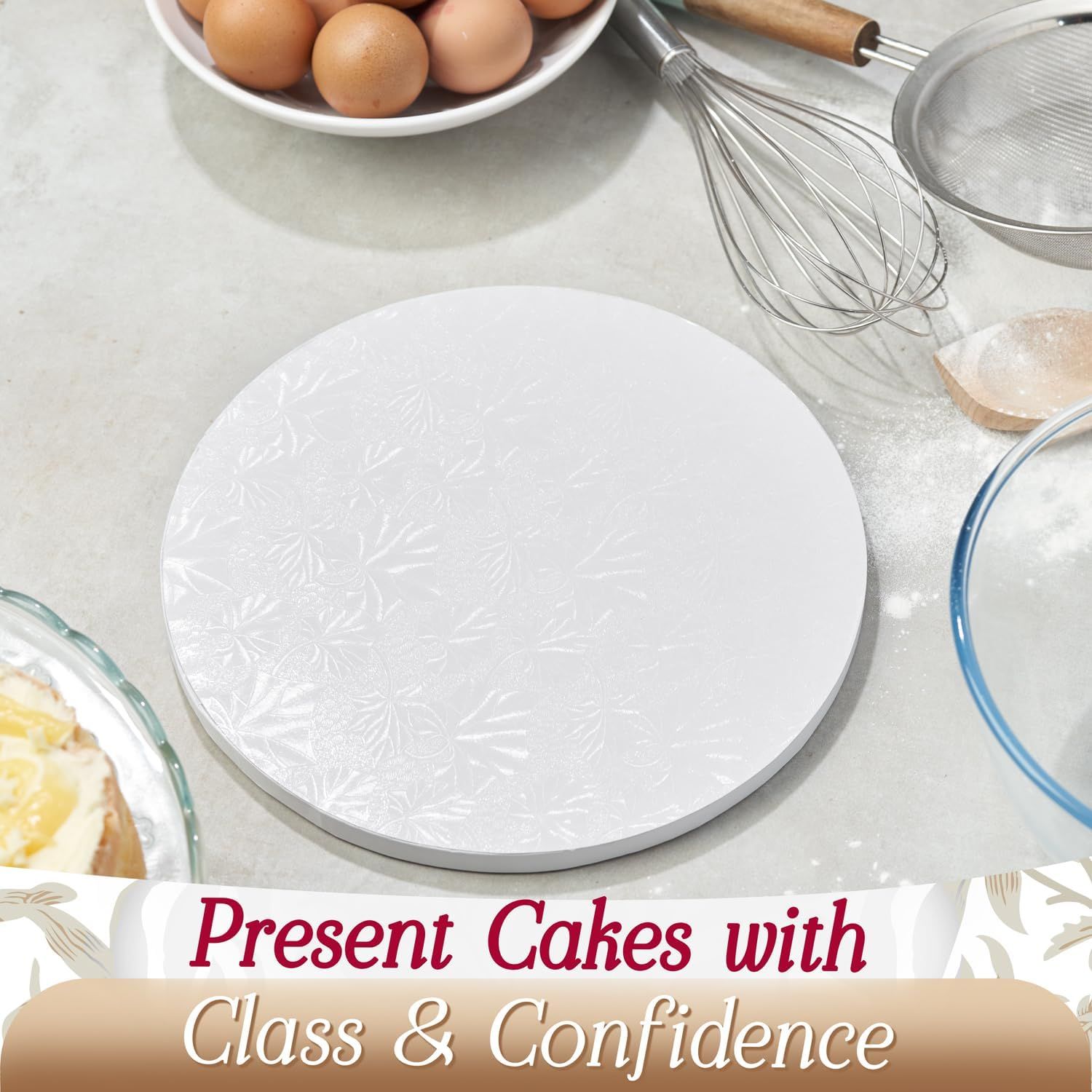 Shows the cake board in a real-world baking environment with eggs, whisk, and other baking tools to help shoppers visualize the product in use.