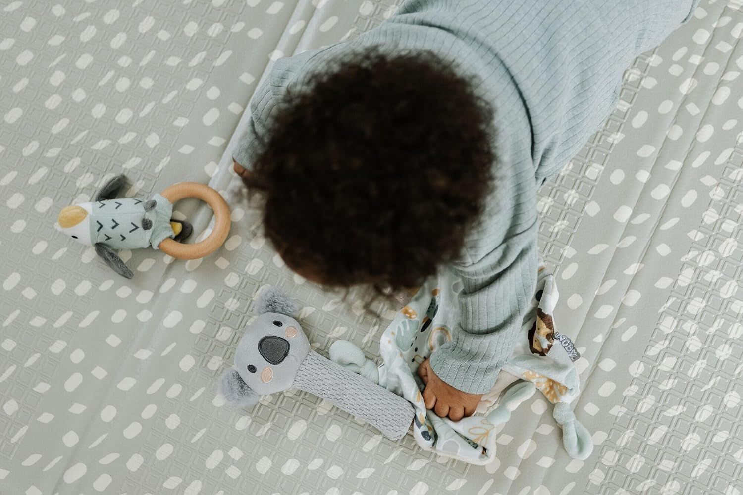 Provides a natural overhead perspective of the baby playing with the toys to show real-world usage and engagement.