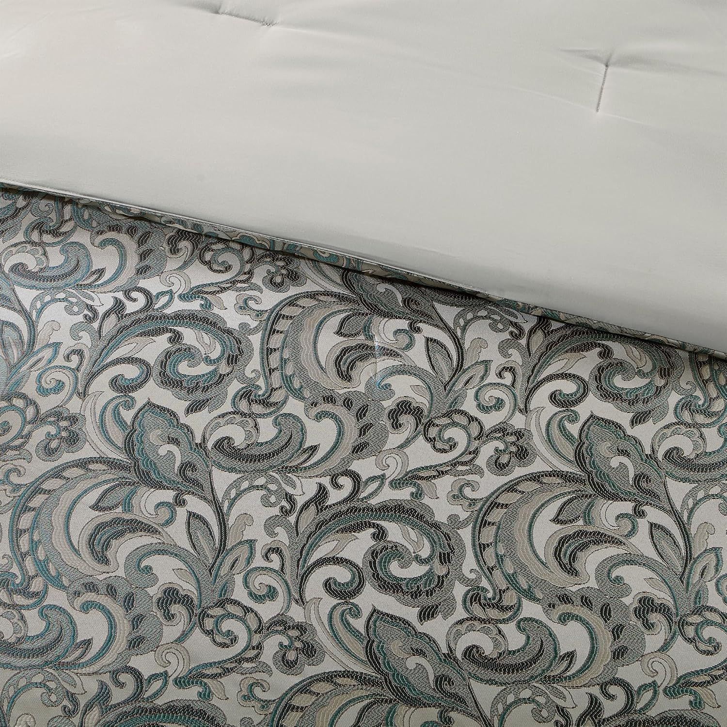 Displays the jacquard pattern detail of the comforter with the fitted sheet to show the design and quality of the fabric.