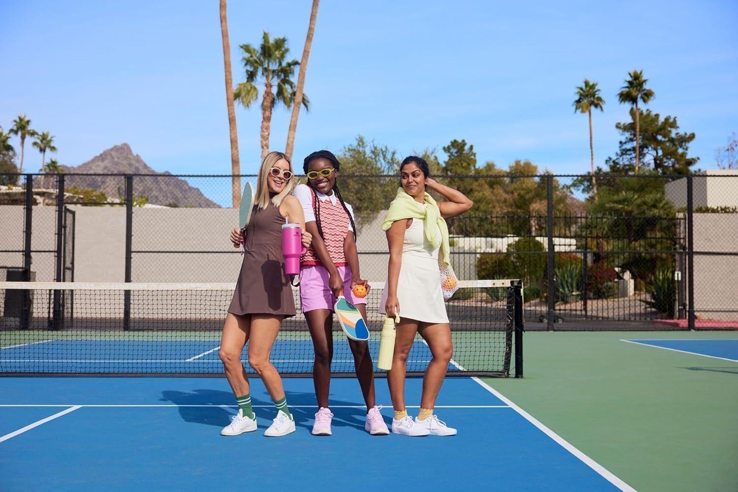 Shows the product in a real-world tennis court setting with people enjoying an active lifestyle, creating an aspirational context for the product without any text overlay.