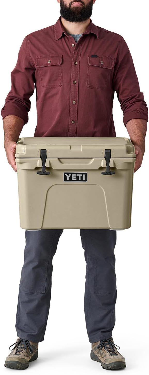 Uses a human figure holding the cooler to provide a visual scale reference, helping shoppers understand the product's physical size and portability.