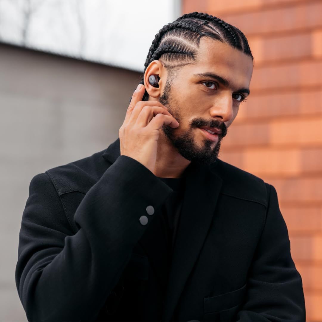 Shows a man wearing the earbuds in an urban setting to help shoppers picture using them in daily life.