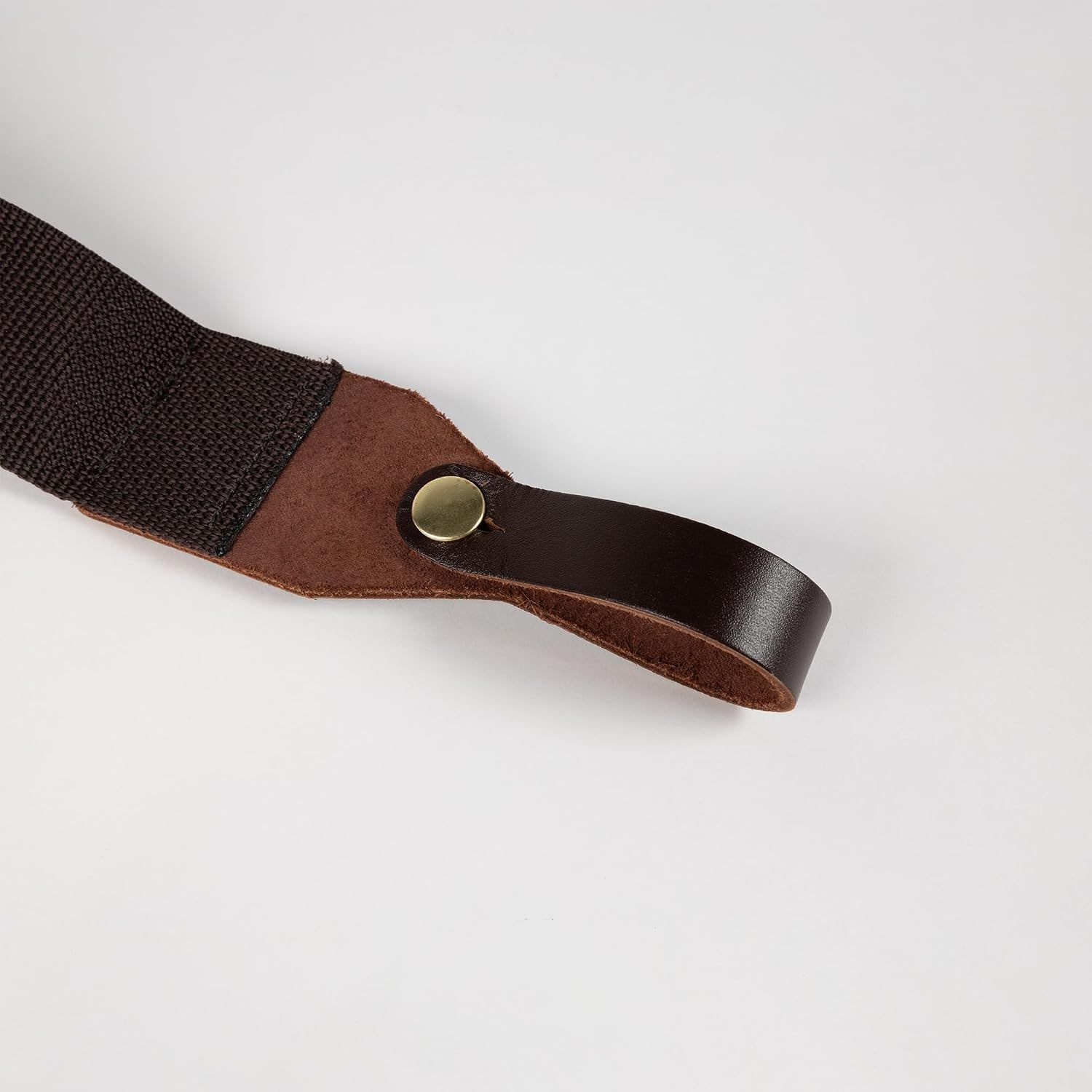 Shows the strap's leather end loop and brass snap up close on a plain background to confirm build quality.