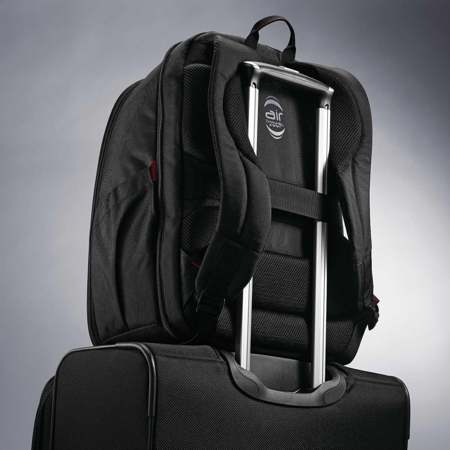 Backpack resting on a suitcase handle shows the trolley sleeve that keeps it secure while traveling.