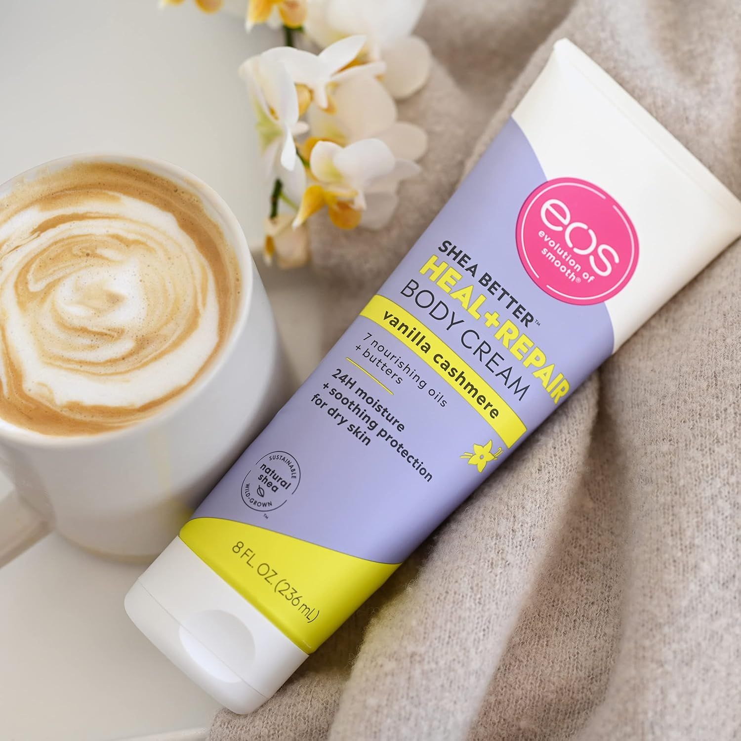 Shows the cream in a warm home setting beside a latte and soft fabric. Helps shoppers picture it as part of a relaxed routine.