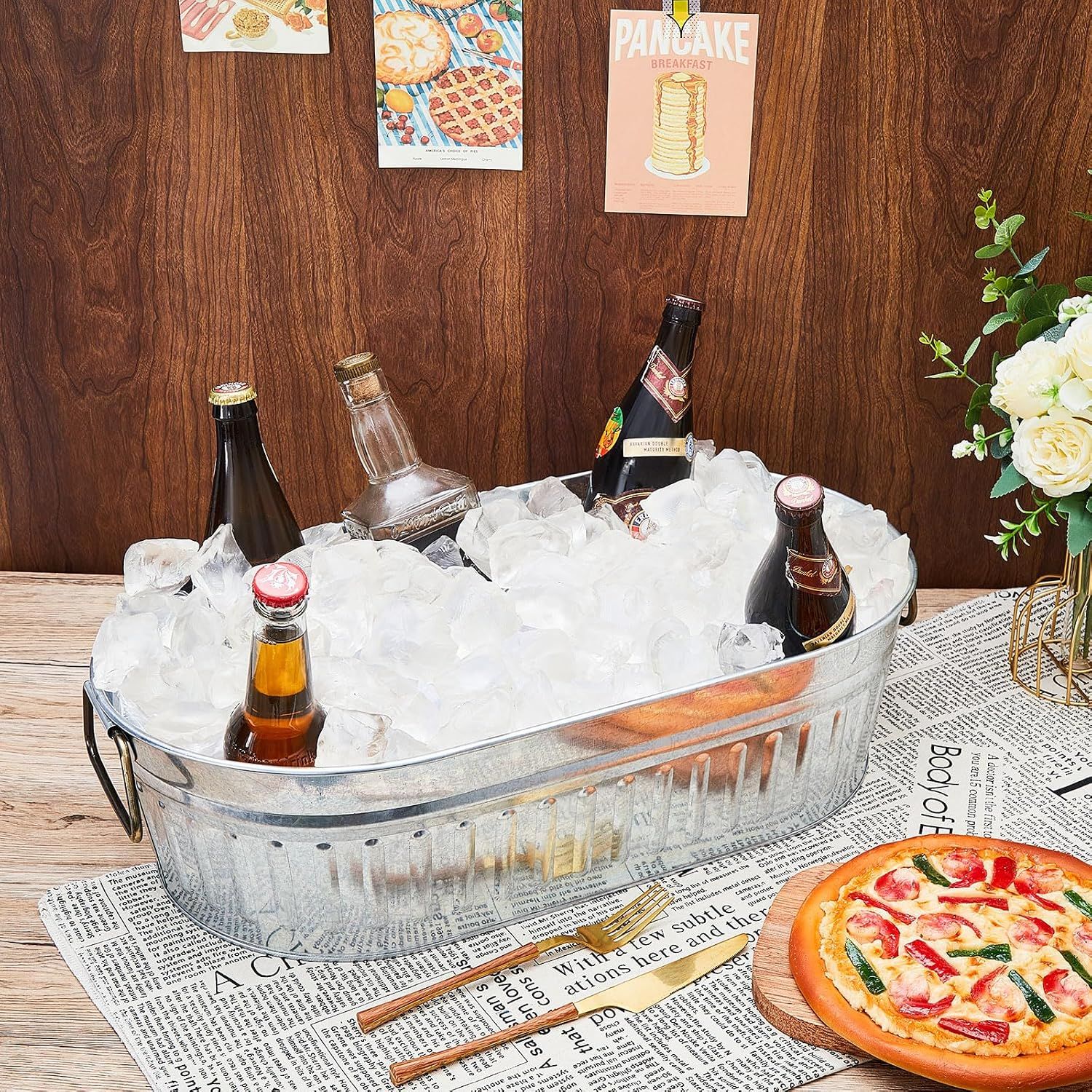 Shows the galvanized tub filled with ice and drinks in a real dining setting so shoppers can picture it at their own gatherings.