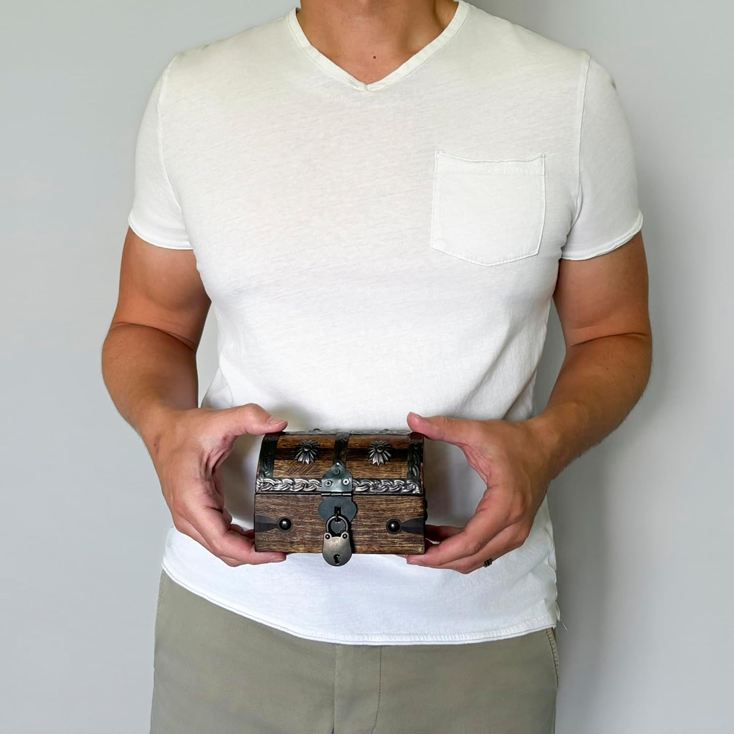 Shows the chest held in a real person's hands to convey its handheld size and rustic look.