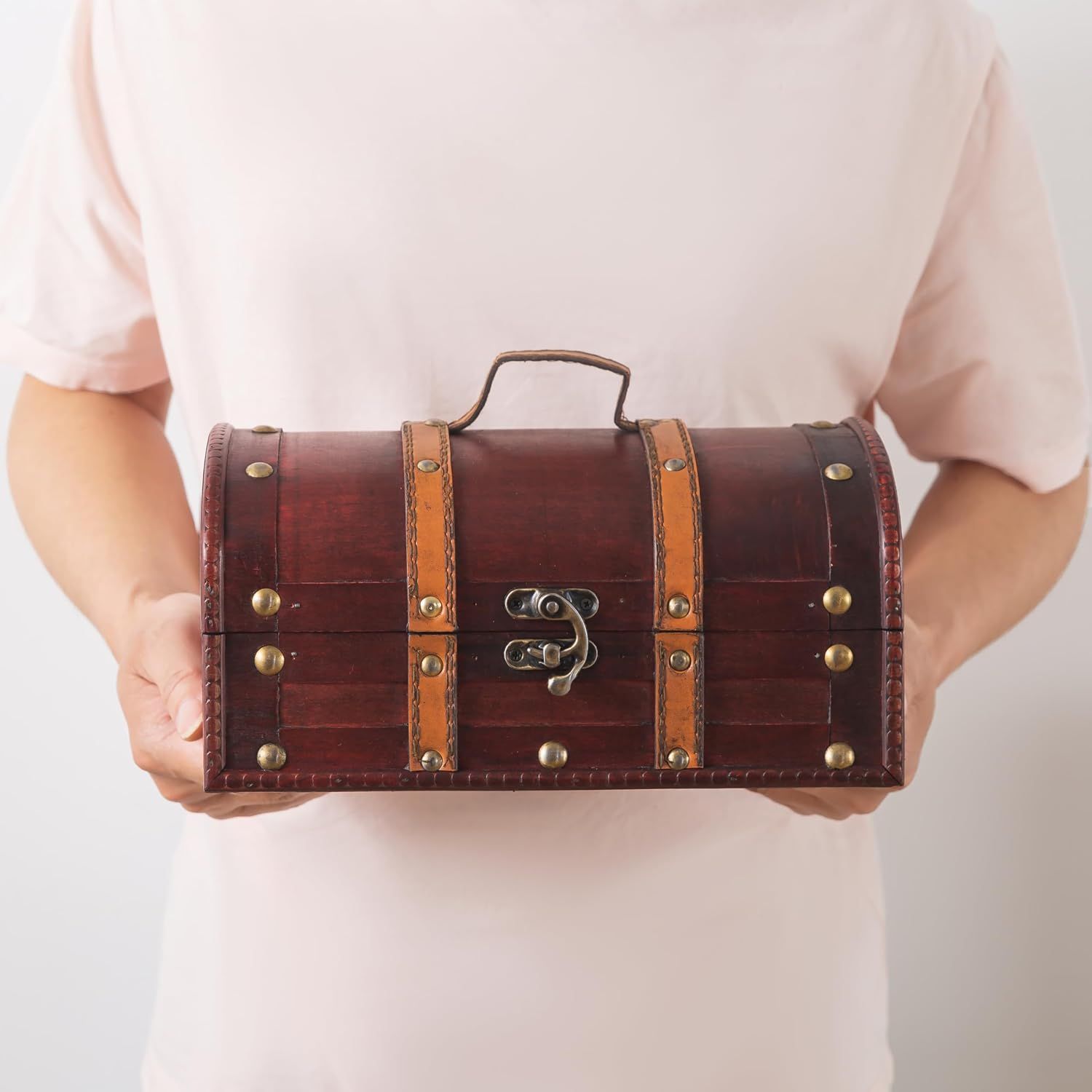 Shows the chest held in hands to convey its compact size and handle-carry convenience.